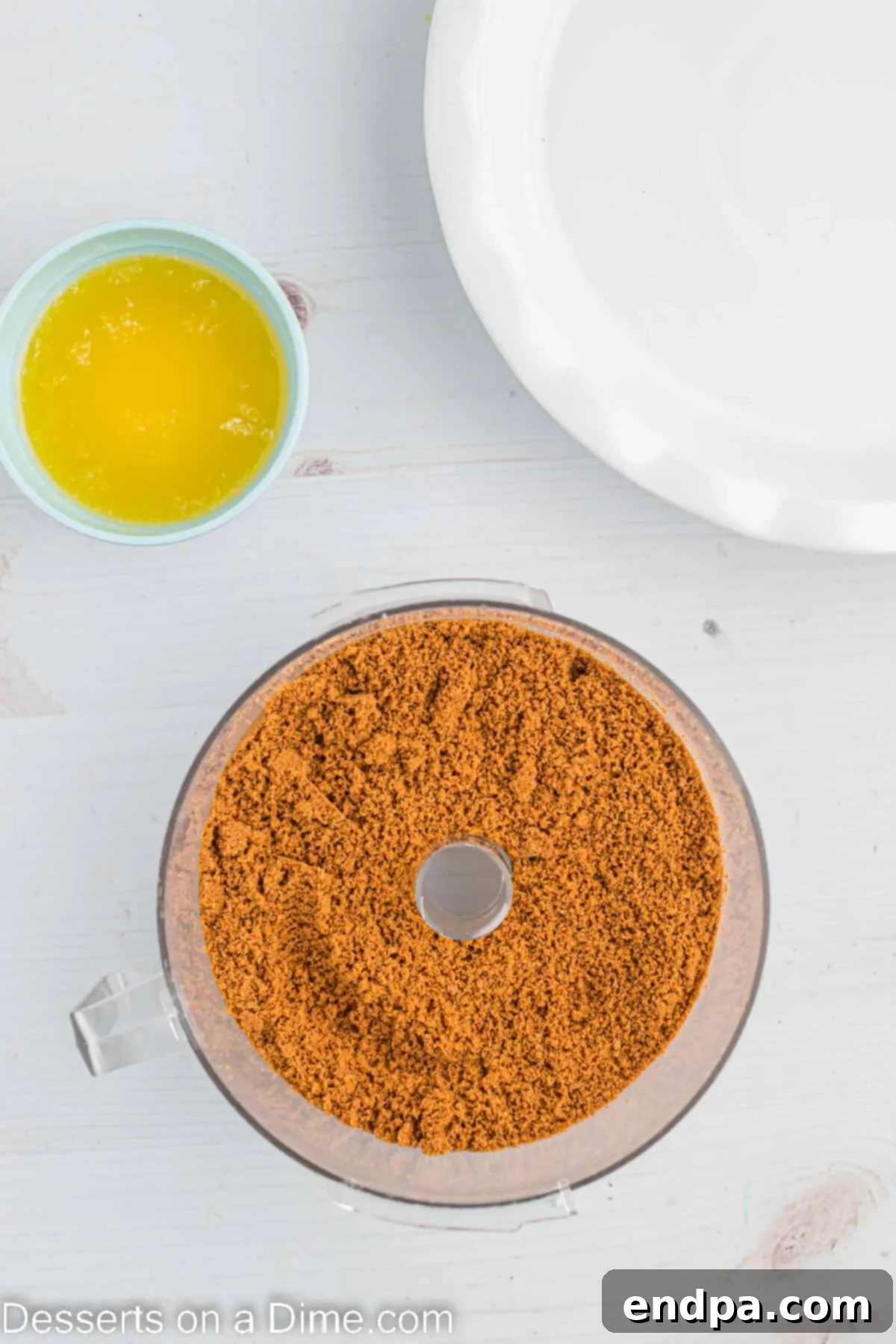 Decadent Cookie Butter Cheesecake 4 Biscoff cookies being crushed in a food processor, creating fine crumbs for the cheesecake crust.