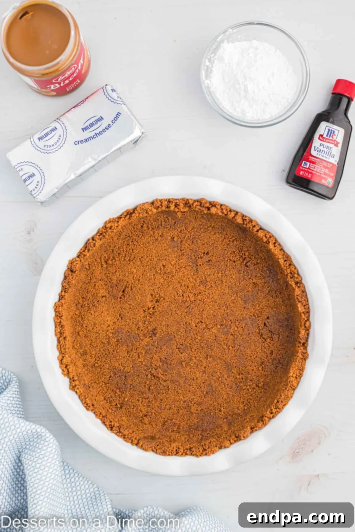 Decadent Cookie Butter Cheesecake 5 Crushed biscoff cookie and butter mixture being pressed firmly into the bottom and sides of a springform pan.