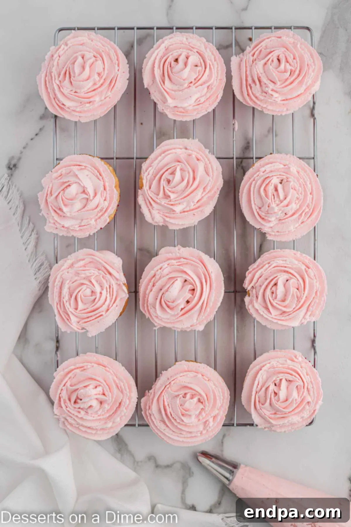 Finished pink buttercream frosting piped onto cooled rose cupcakes.