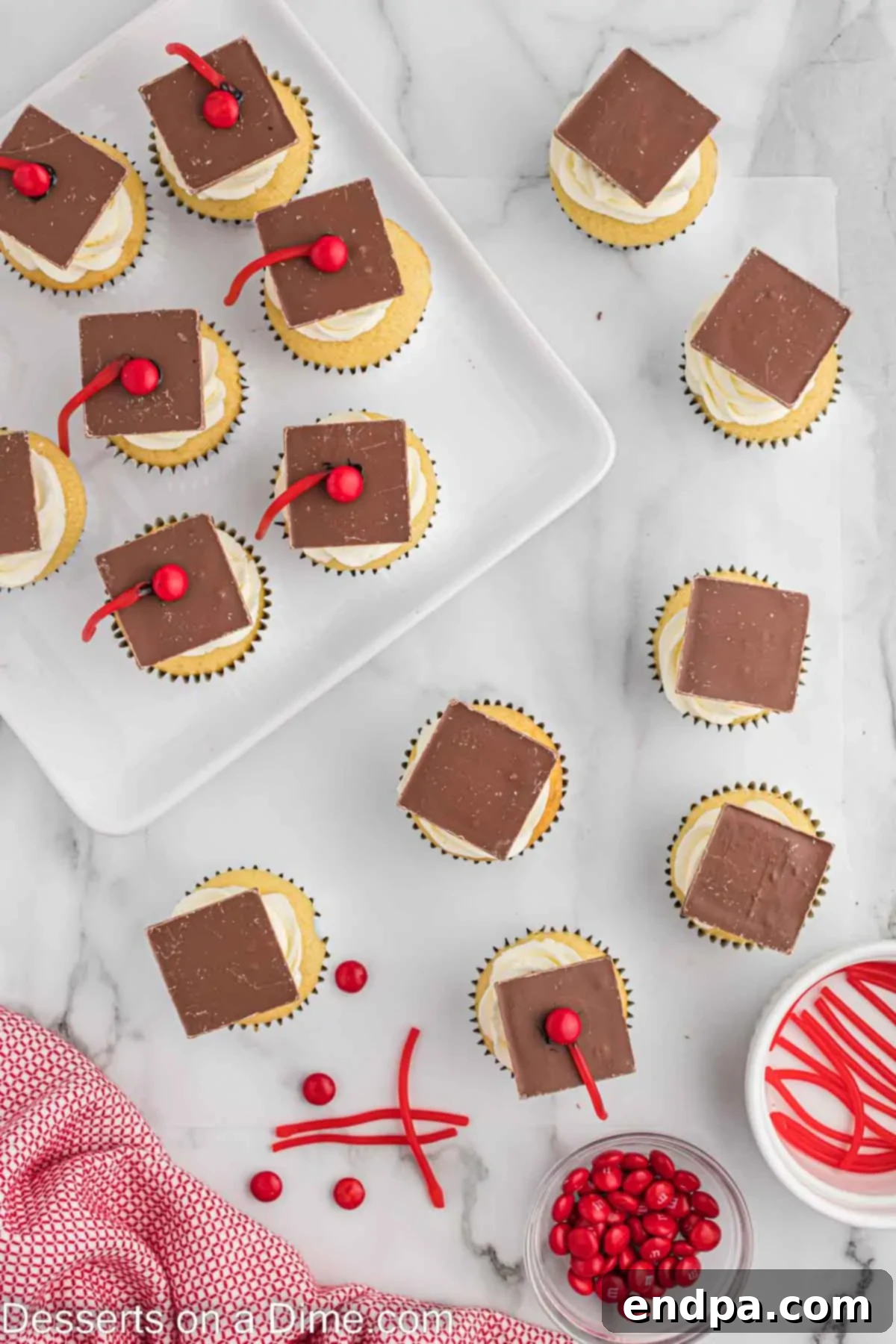 M&M's and string licorice attached to each chocolate square on cupcake. 