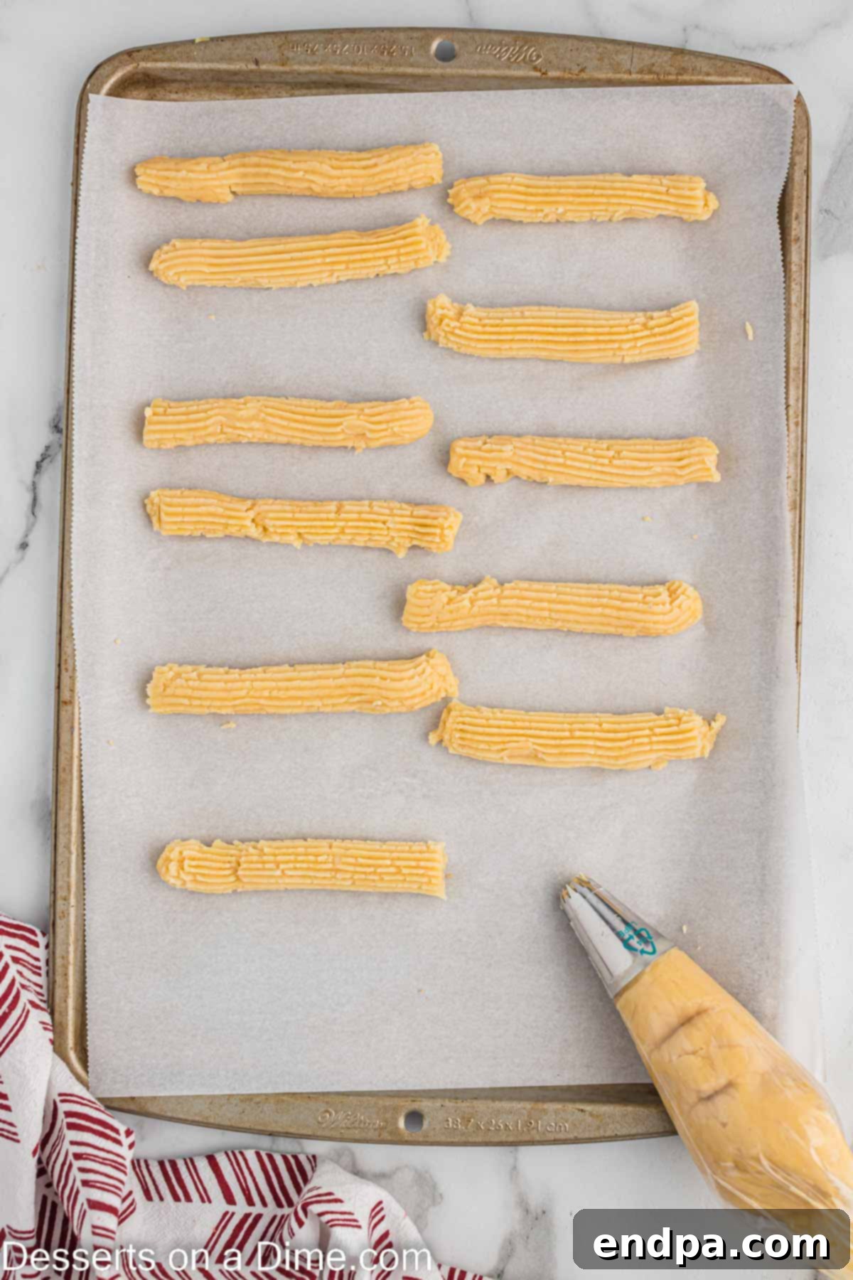 Churros dough piped onto a baking sheet.