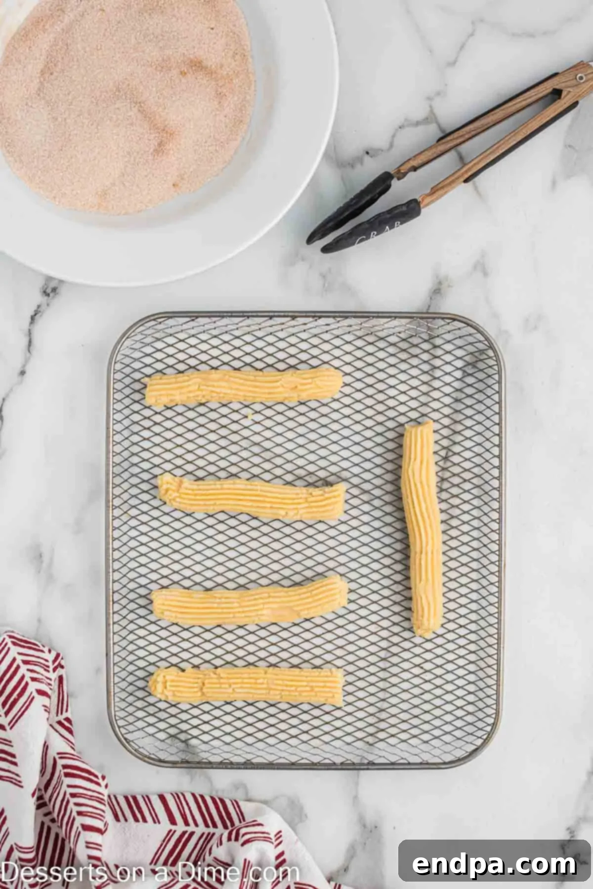 Frozen churros on an air fryer basket liner, ready to be cooked.