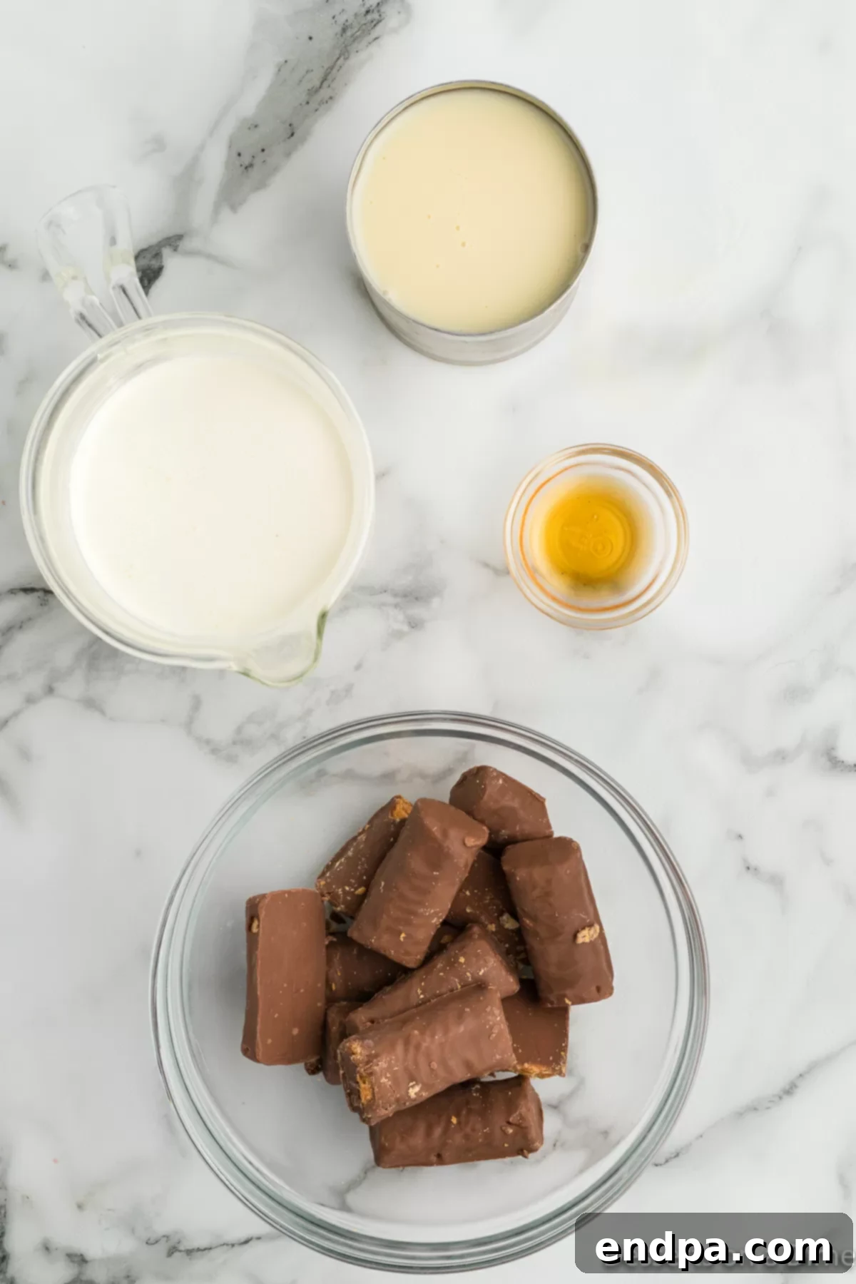 Homemade Butterfinger Crunch Ice Cream 3 Ingredients for Butterfinger ice cream: sweetened condensed milk, vanilla extract, heavy whipping cream, and mini Butterfinger candy bars laid out on a kitchen surface.