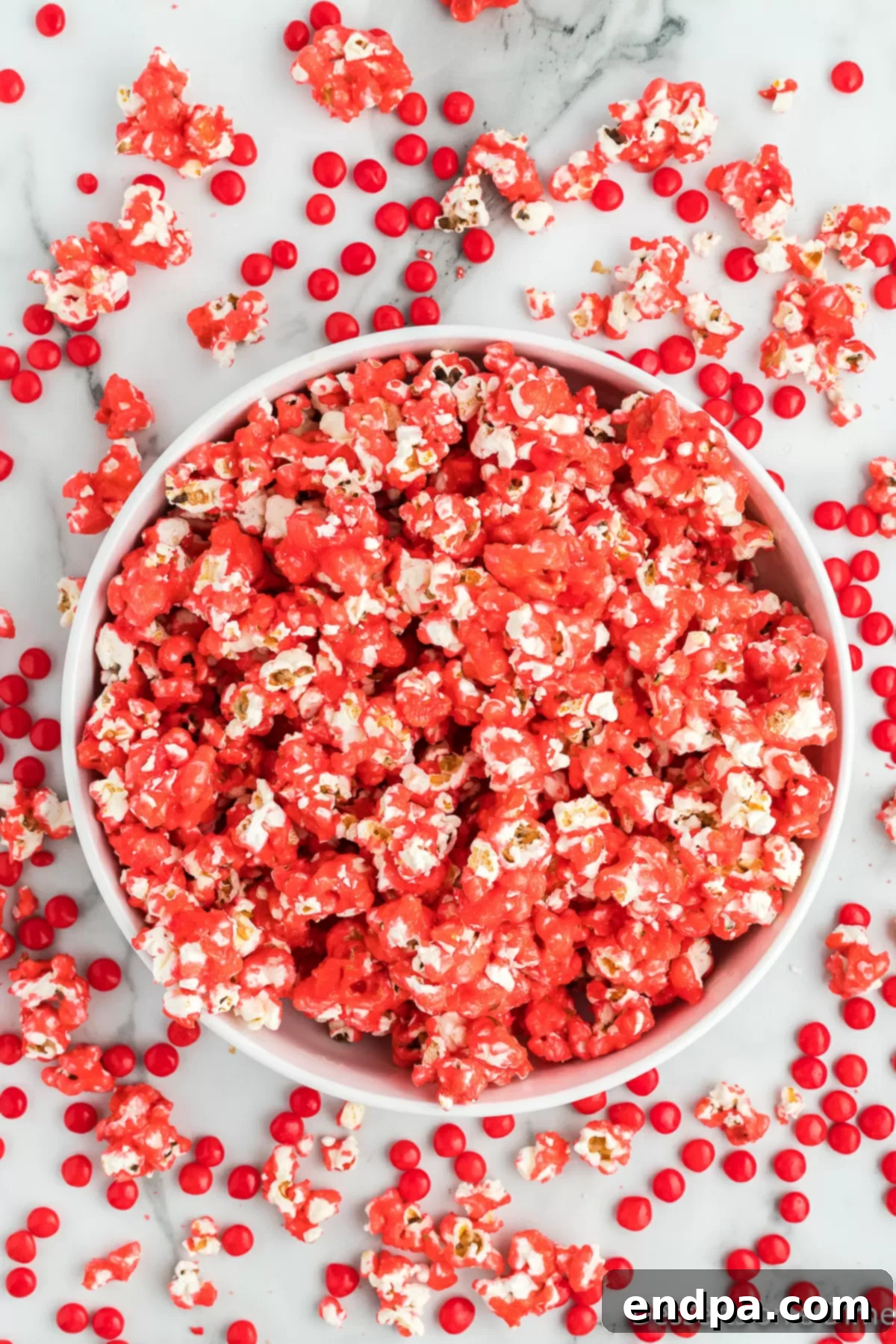 A bowl brimming with glistening, red hot cinnamon popcorn, ready to be enjoyed as a festive snack or dessert.