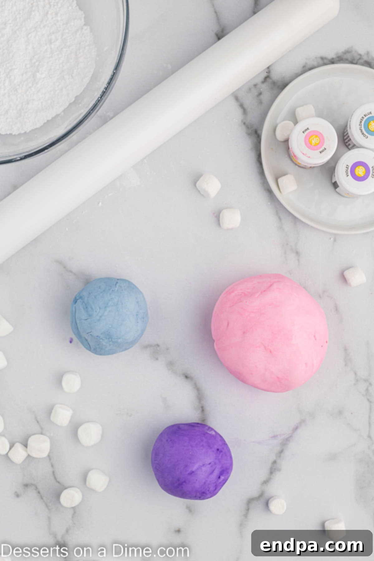 Foolproof Marshmallow Fondant 7 Balls of marshmallow fondant with gel food coloring added, ready to be kneaded for even color distribution.
