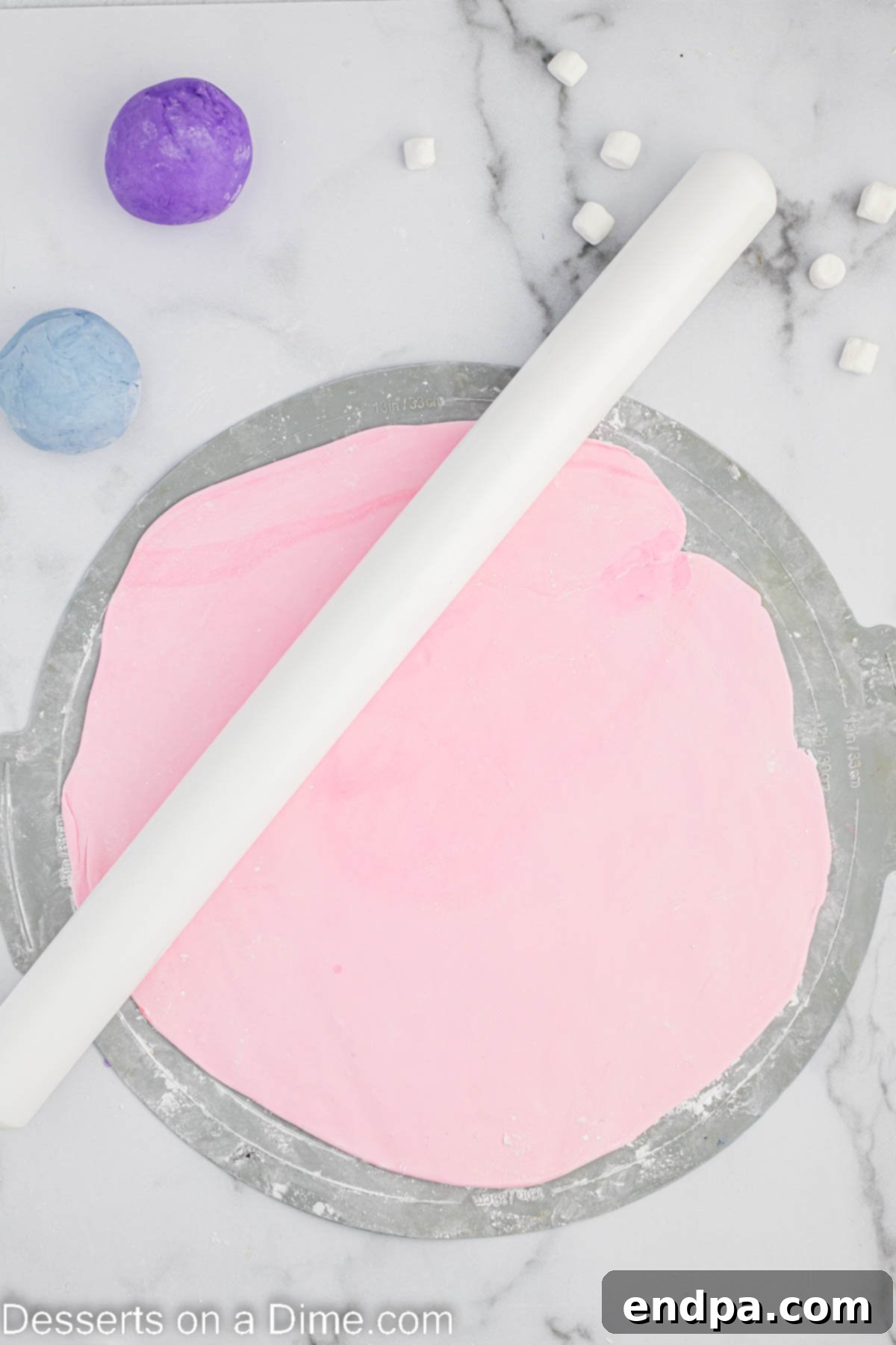 Foolproof Marshmallow Fondant 8 Pink marshmallow fondant rolled out thinly on a powdered sugar-dusted surface.