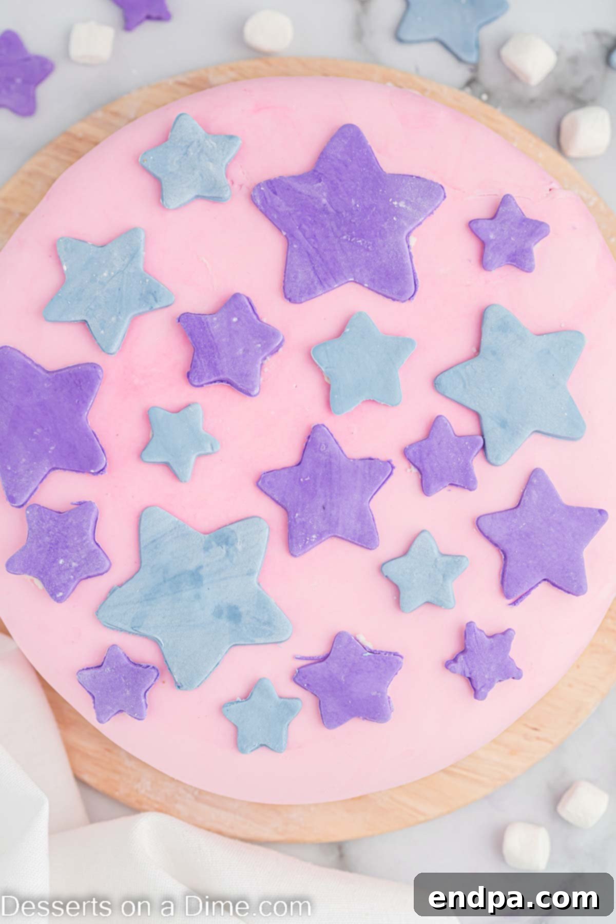 Foolproof Marshmallow Fondant 9 Marshmallow fondant stars cut out and placed as decorations on a cake.