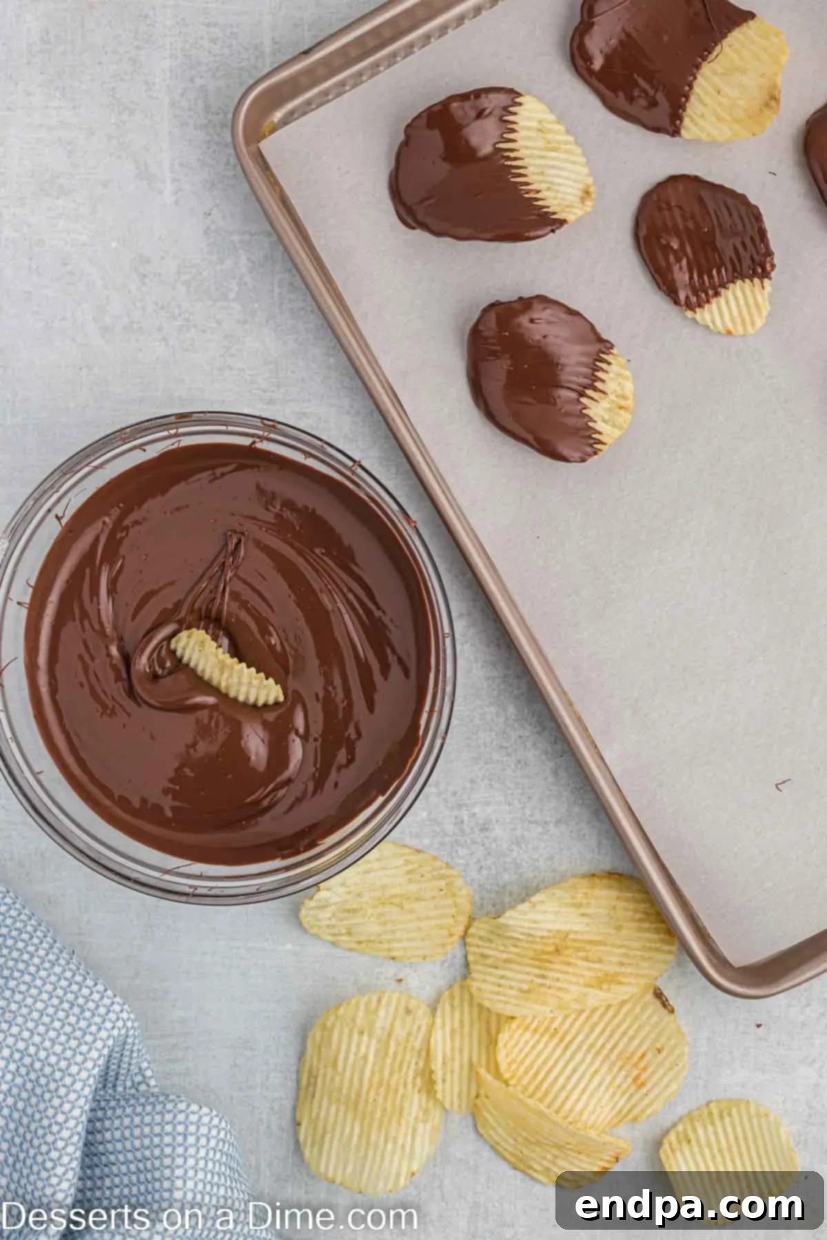 A potato chip being carefully dipped into a bowl of smooth, melted chocolate.