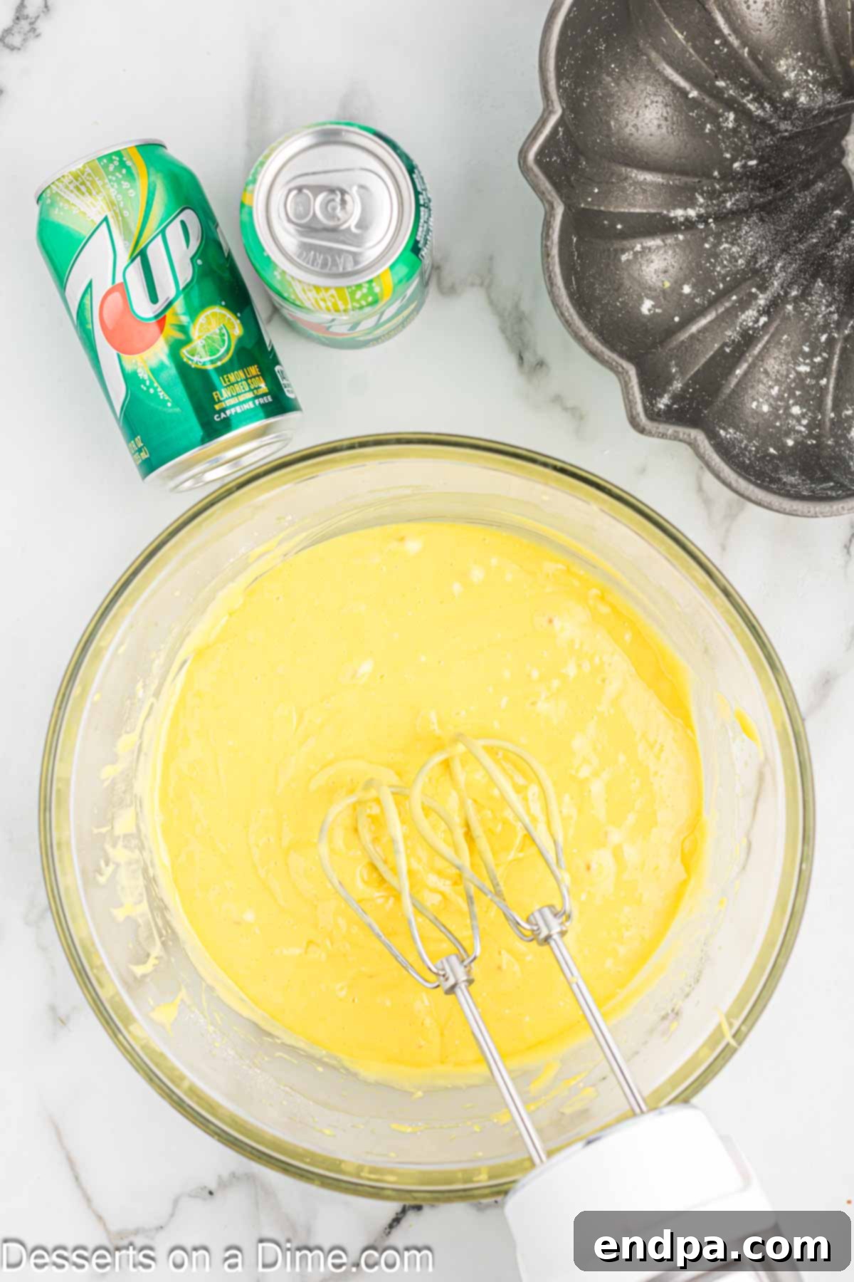 Classic 7 Up Pound Cake 4 Cake batter being mixed in a large bowl with a handheld mixer, showing its smooth, yellow consistency.