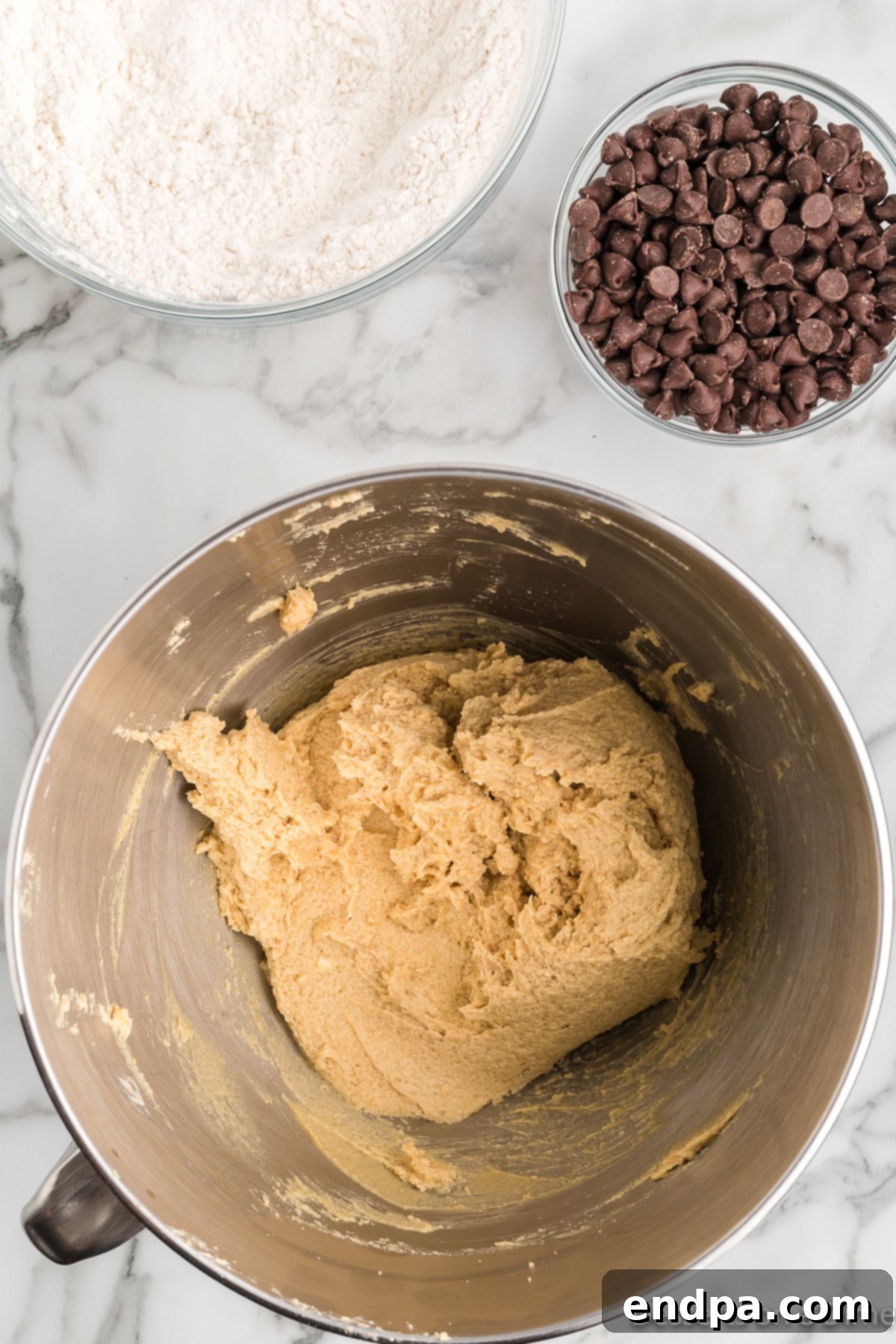 Wet and dry ingredients partially combined in a mixer, showing a textured cookie dough.