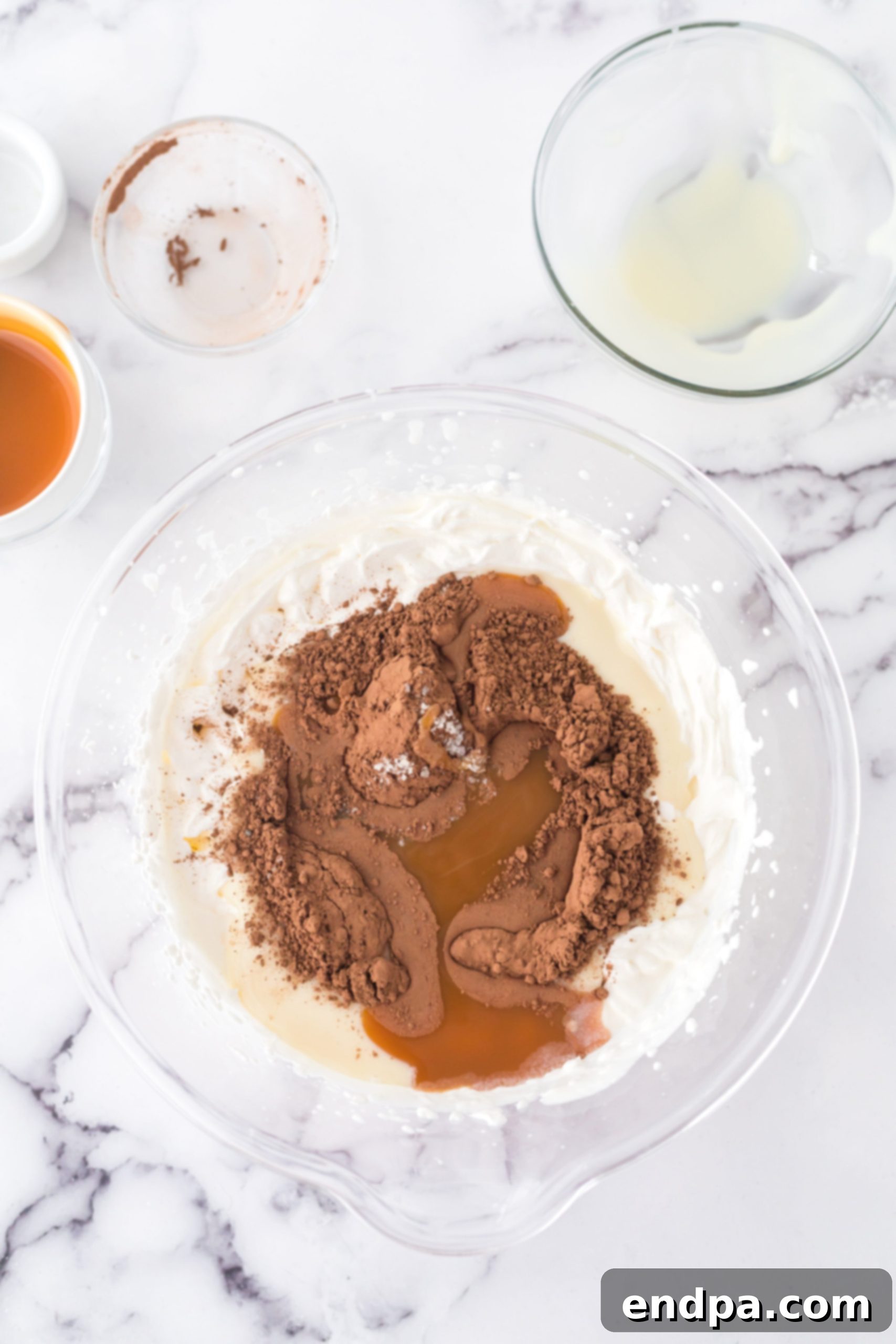 Golden Swirl Chocolate Delight 5 A bowl filled with whipped cream, sweetened condensed milk, cocoa powder, and caramel sauce, ready to be gently folded together.