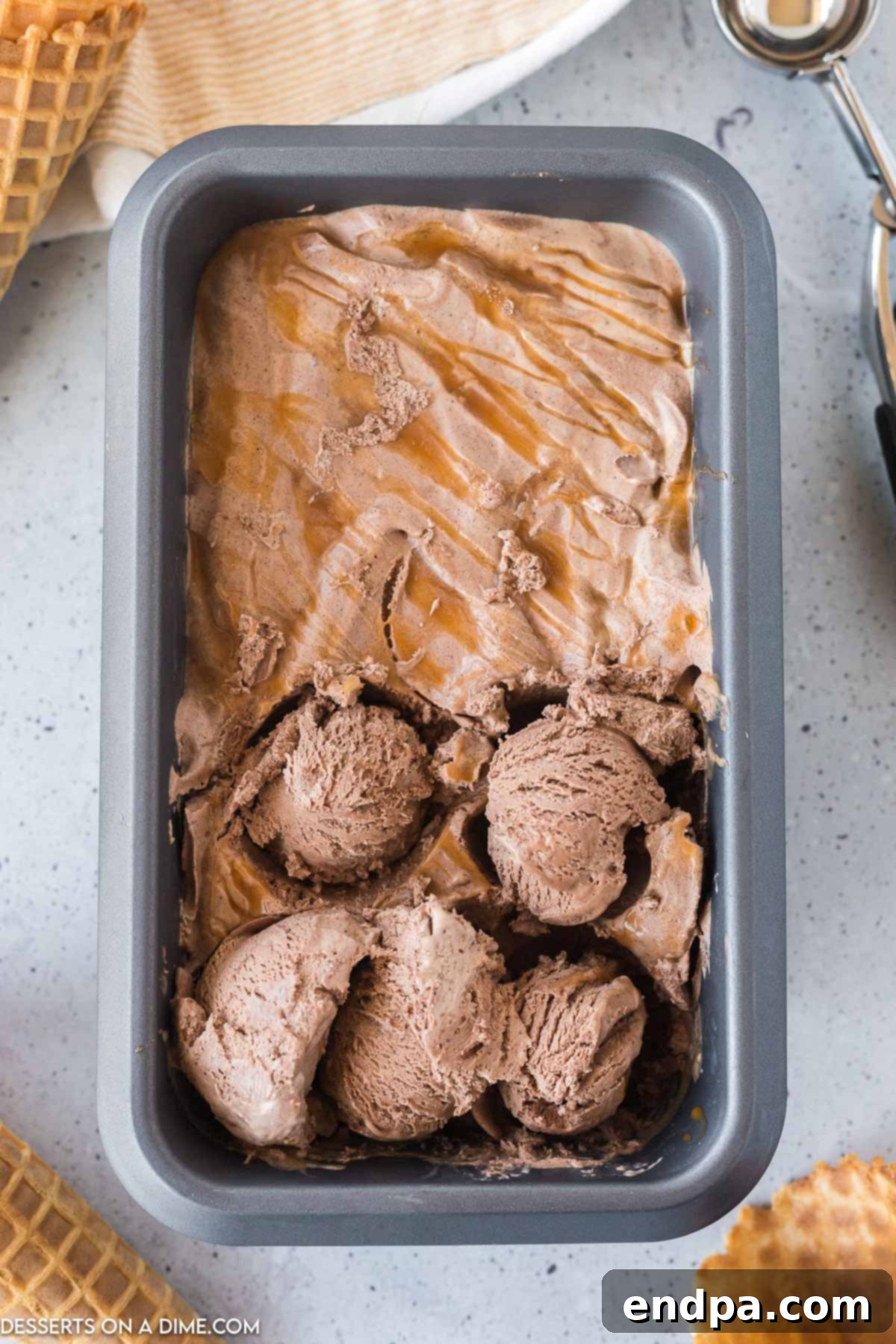 Golden Swirl Chocolate Delight 7 A hand scooping a generous portion of firm chocolate caramel ice cream from the loaf pan, ready to be served.