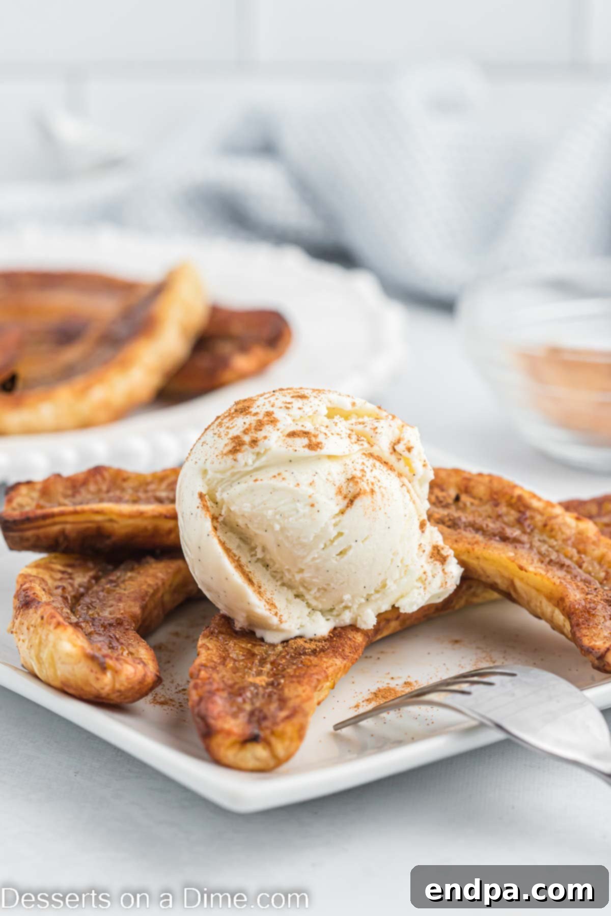 Air fryer bananas on a plate with a scoop of vanilla ice cream and a drizzle of caramel sauce.