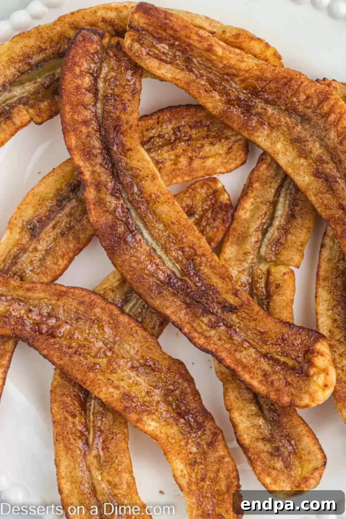 Air Fryer bananas on a plate, garnished with a sprinkle of cinnamon and a mint leaf.
