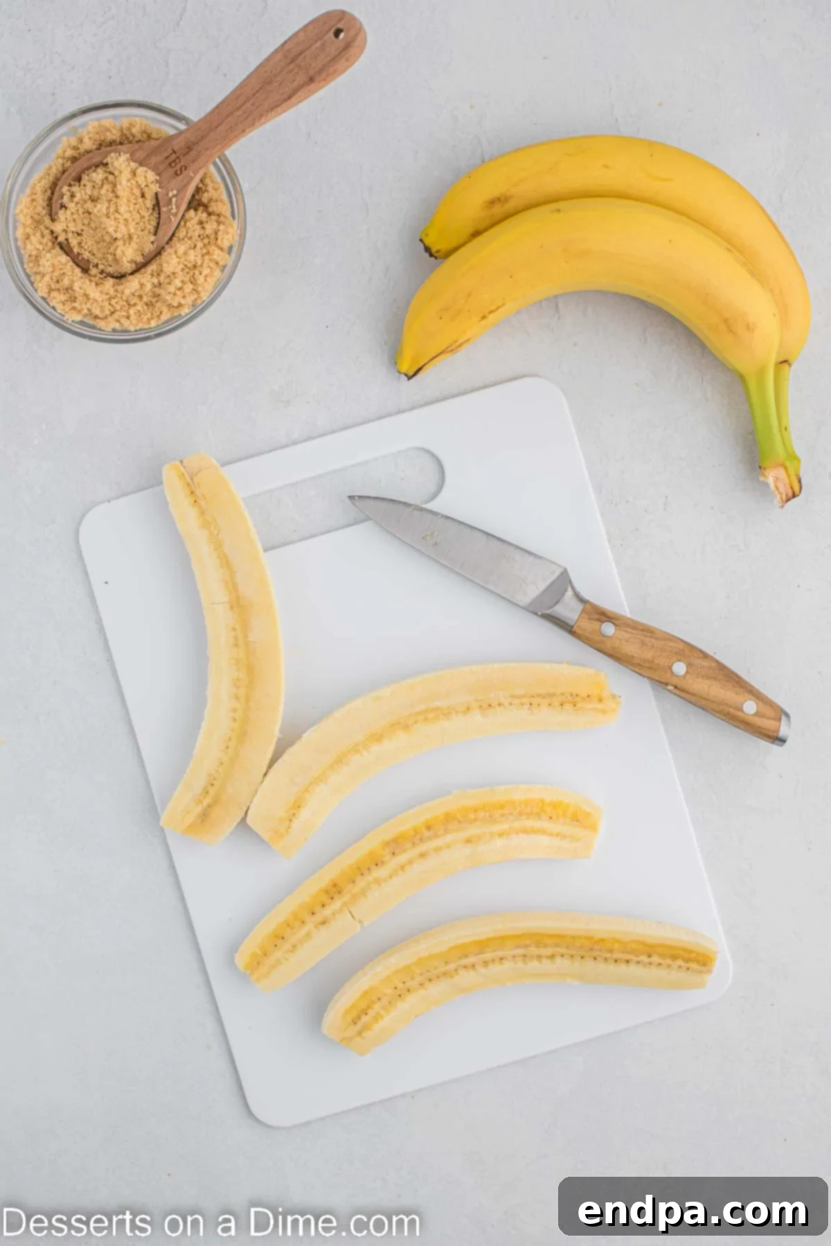 Bananas sliced in half lengthwise on a cutting board.