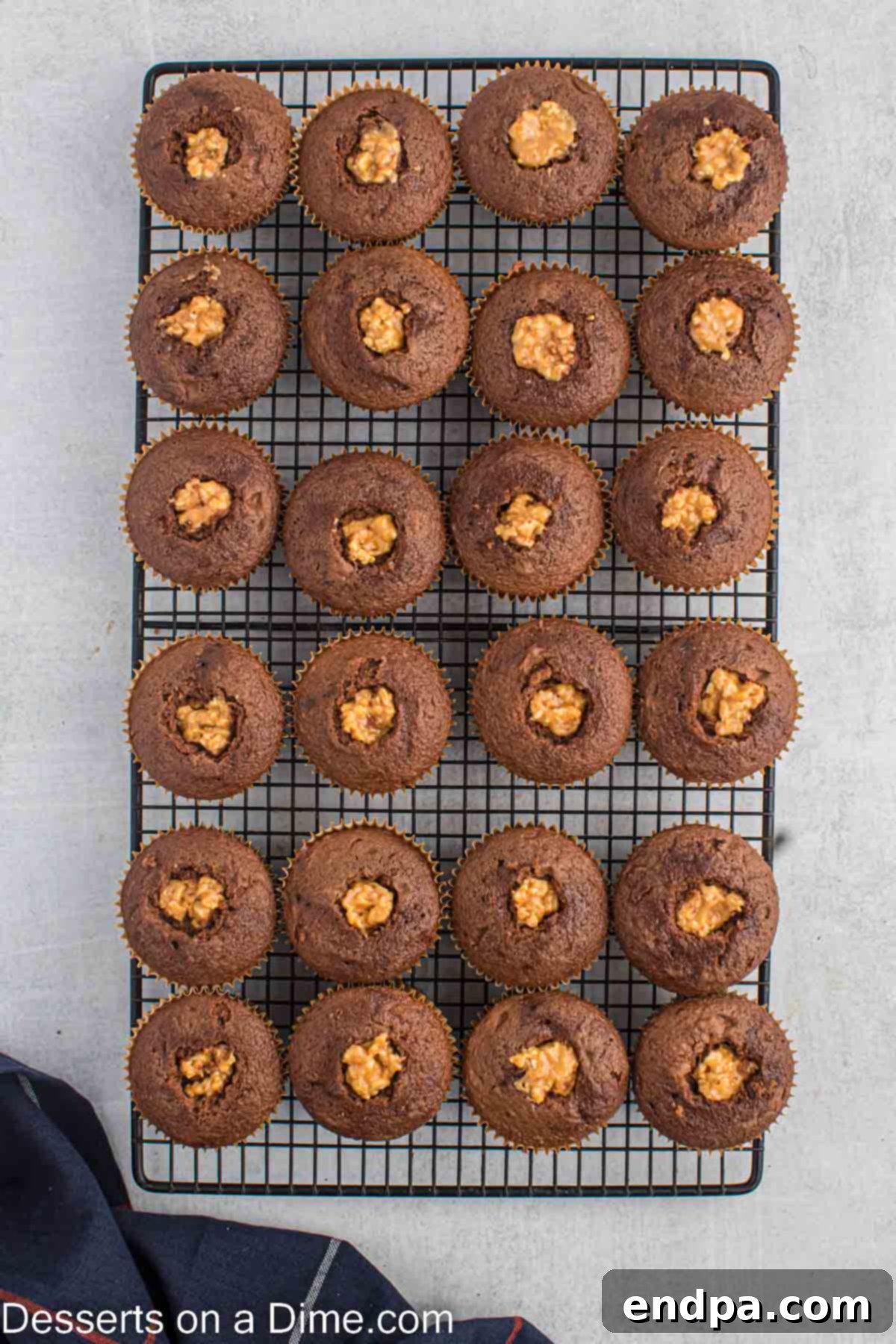 Caramel peanut filling being spooned into the cored cupcakes.
