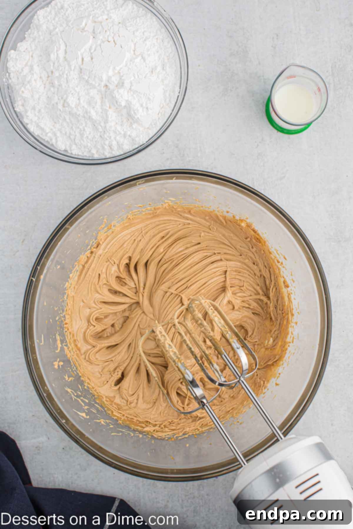 Butter and peanut butter being creamed together in a mixing bowl for the frosting.