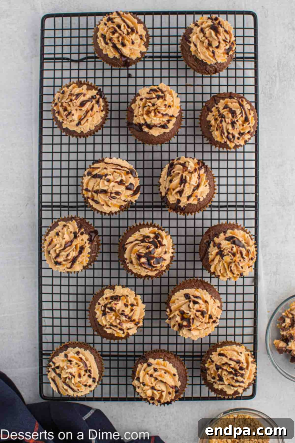 Frosted Snickers cupcakes neatly arranged on a wire rack.