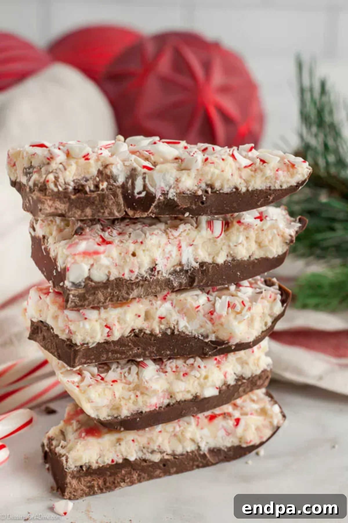 Easy Homemade Peppermint Bark: A festive and delicious holiday chocolate treat. Stacked pieces of homemade Chocolate Peppermint Bark, showcasing its distinct layers and festive candy cane topping.