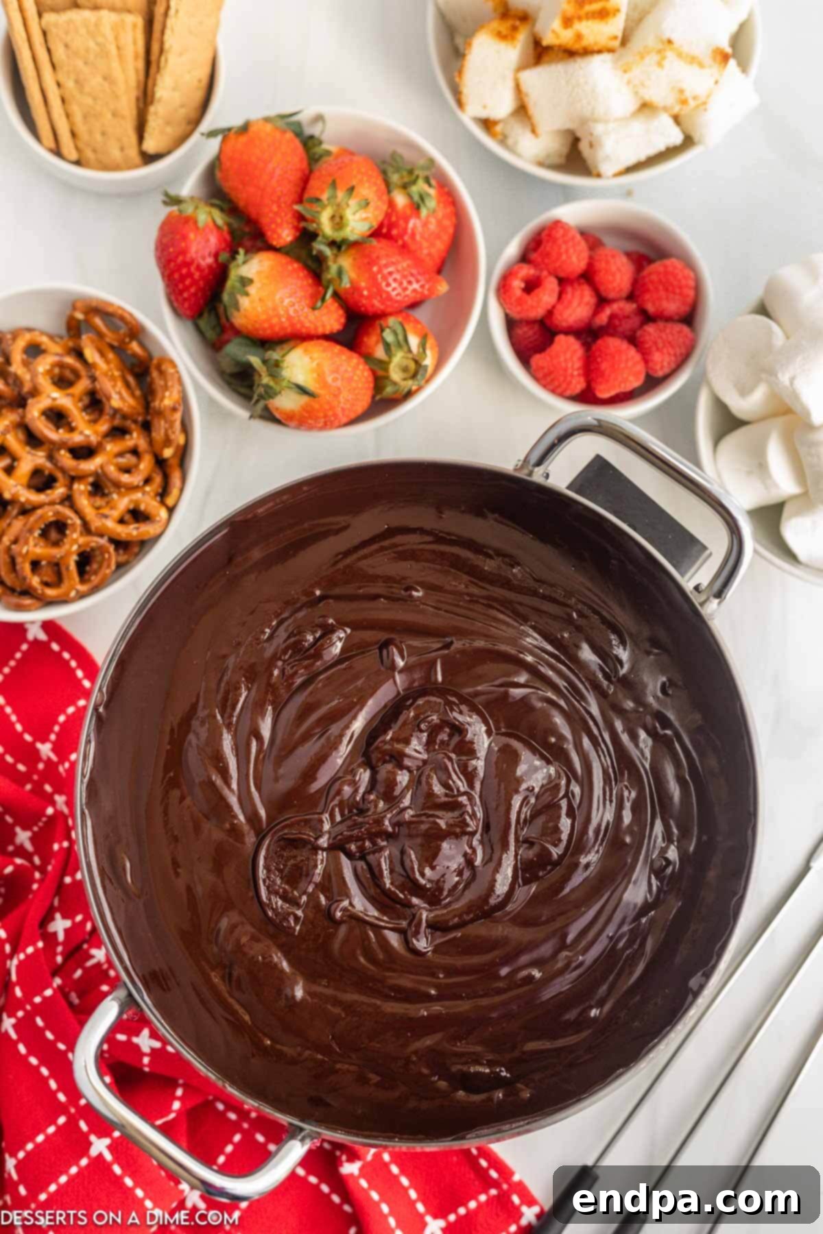 Chocolate fondue in a pot surrounded by various dippers, ready for a party.
