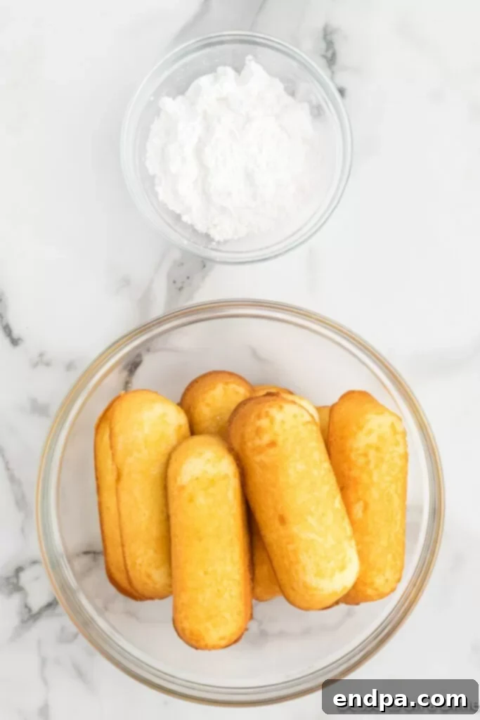 A bowl filled with classic Twinkies sits next to a bowl of sifted powdered sugar, ready for air frying and topping.