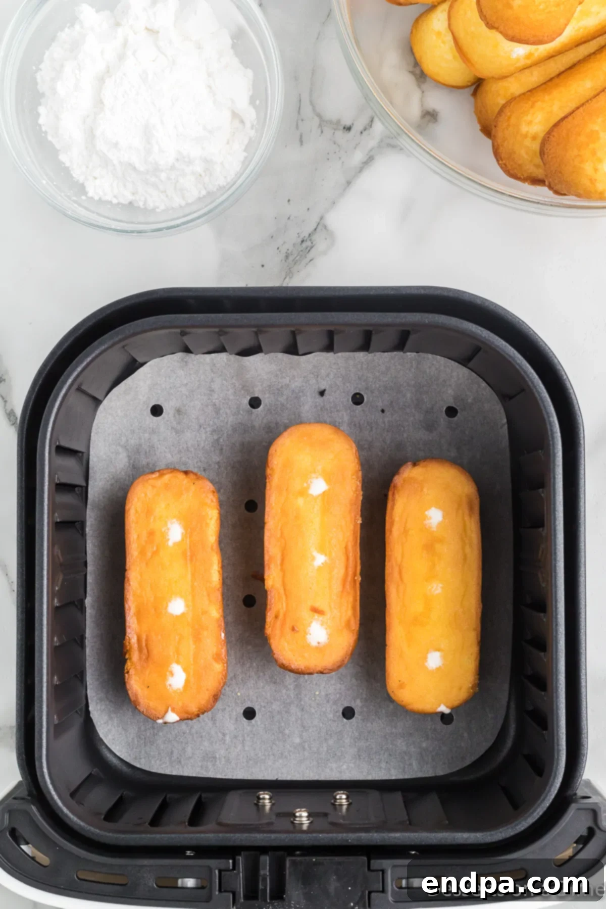 Twinkies carefully flipped over in the air fryer basket, ready for the final cooking stage.