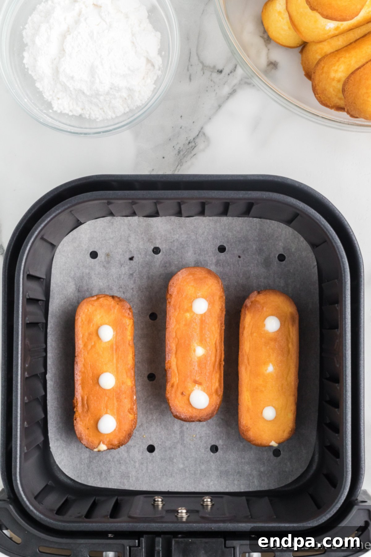 Golden brown air-fried Twinkies, perfectly cooked and ready to be removed from the air fryer.