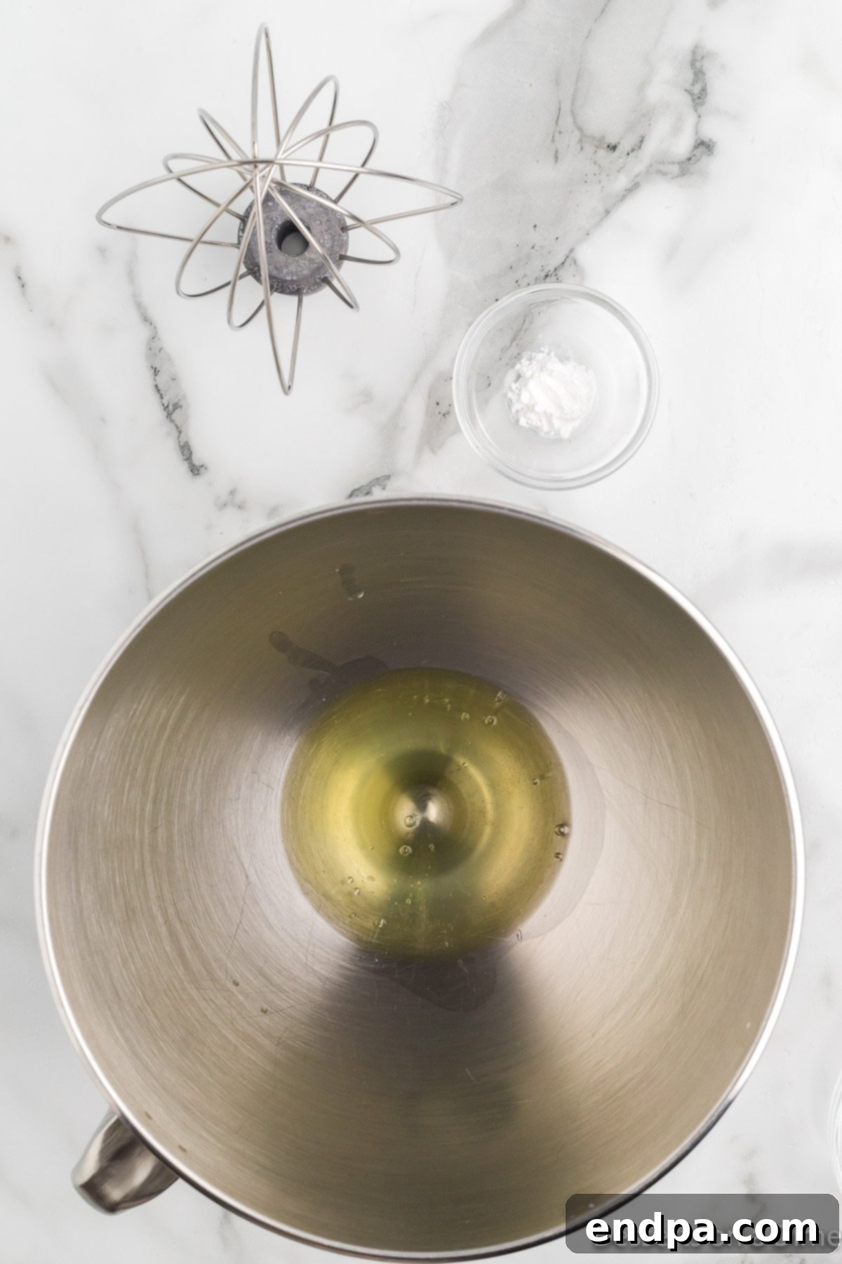 A candy thermometer immersed in the simmering sugar syrup mixture in a saucepan.