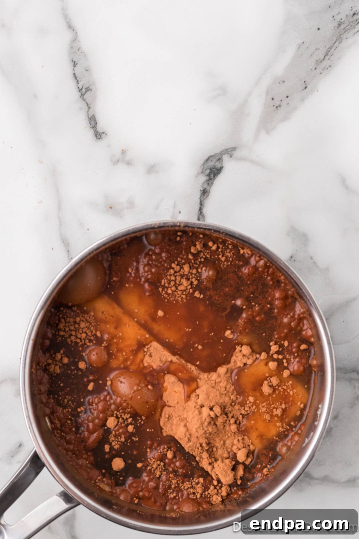 Saucepan with butter, cocoa powder, salt, and water being combined on a stovetop.