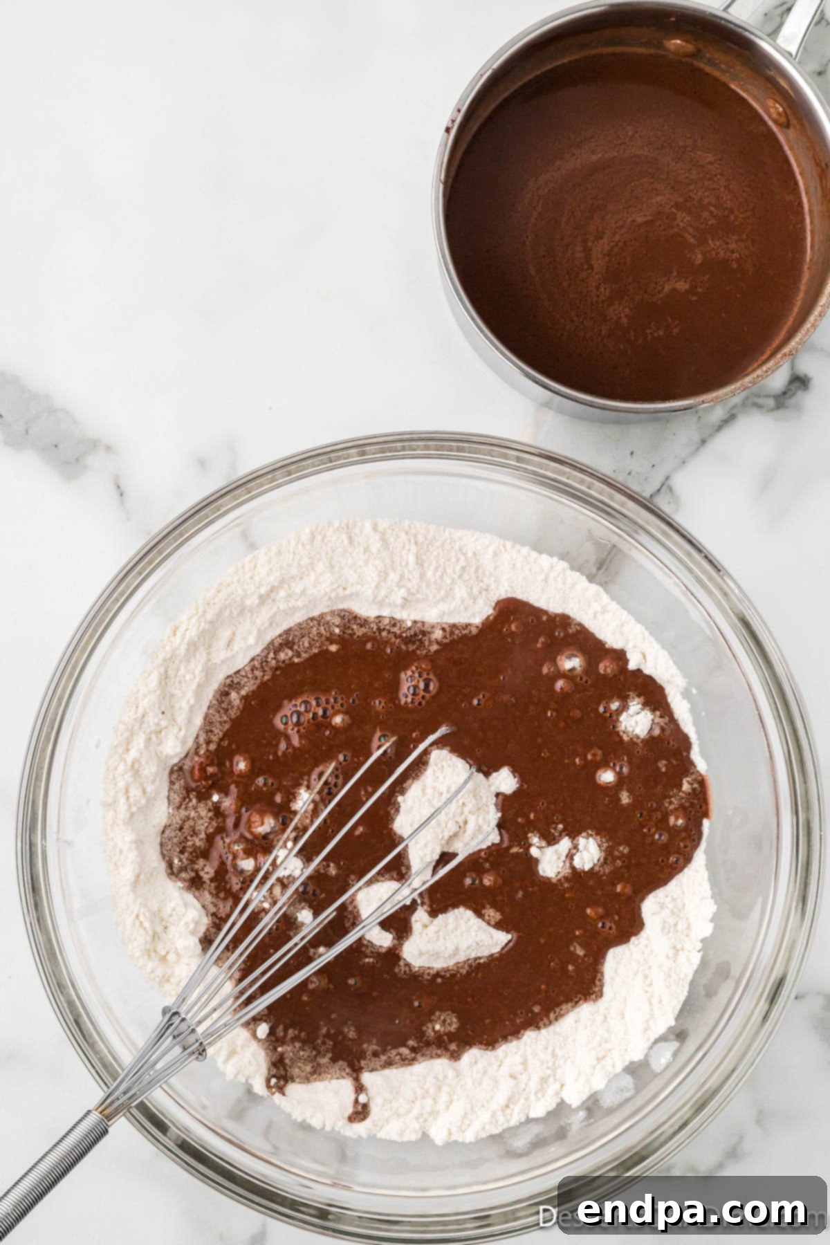 Melted butter and cocoa mixture being added to the dry ingredients in a large bowl.