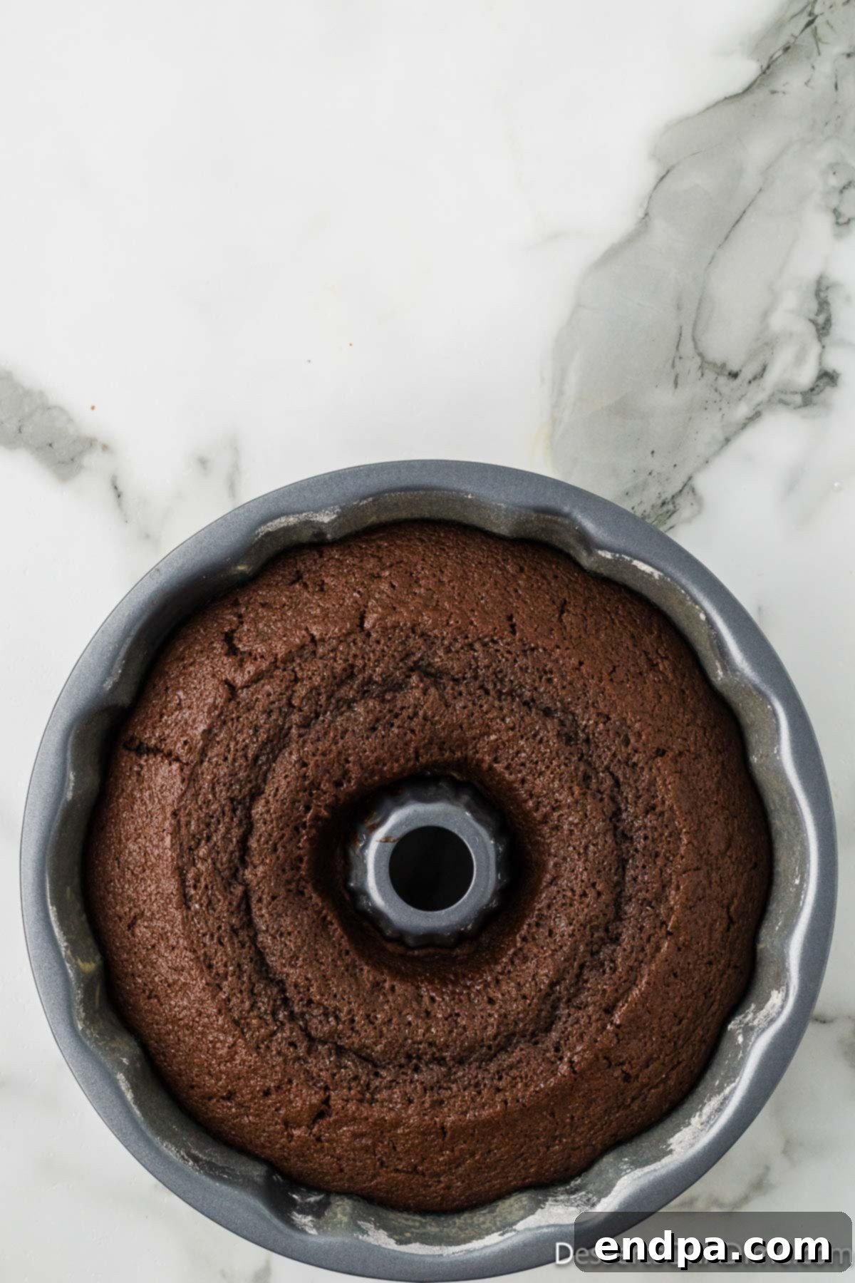 Freshly baked chocolate bundt cake cooling in the pan after removal from the oven.
