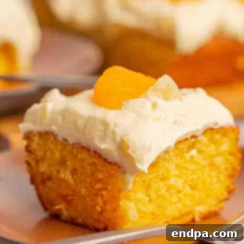 A slice of moist orange pineapple cake, topped with a creamy frosting and served on a plate with a fork.