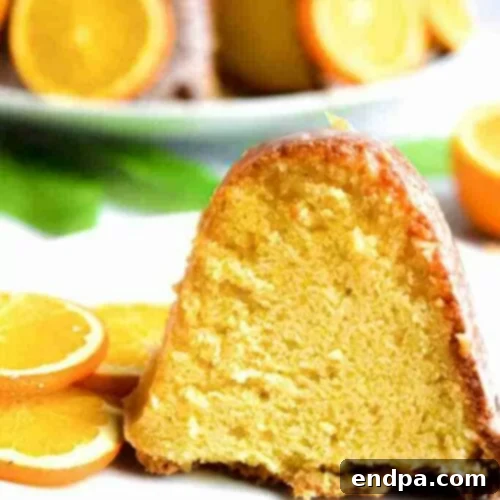 A perfectly baked orange bundt cake, sliced and adorned with fresh orange segments, on a plate.