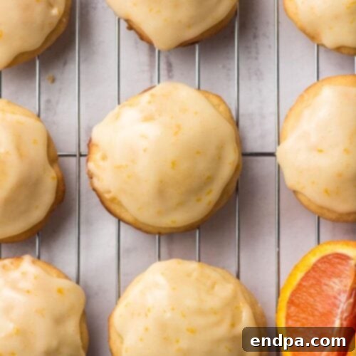 Freshly baked orange cookies, glistening with orange icing, cooling on a wire rack.