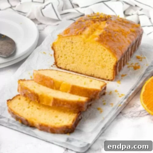 Slices of golden orange pound cake, beautifully arranged on a wooden cutting board.