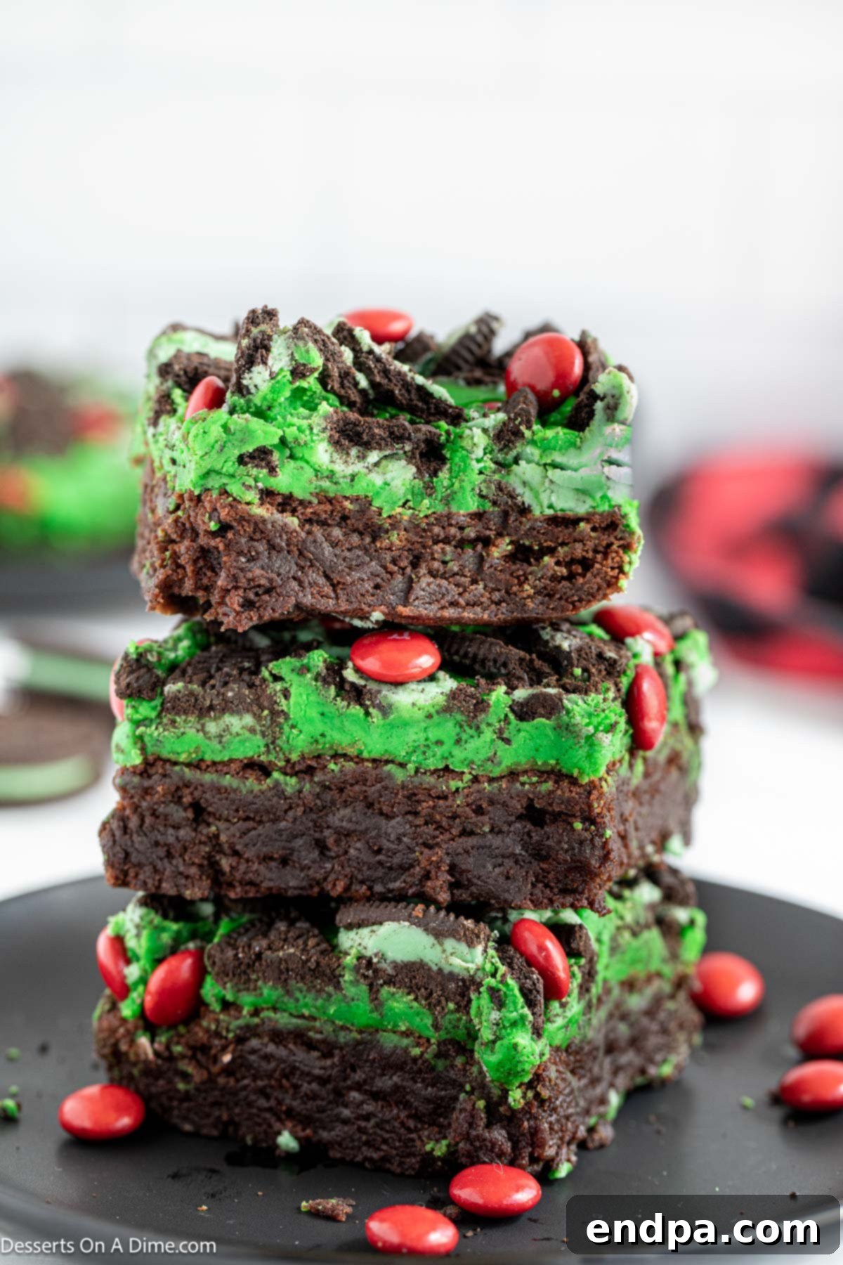 Grinch Green Brownies 2 Grinch brownies cut and stacked together, showcasing the green topping and red candies.