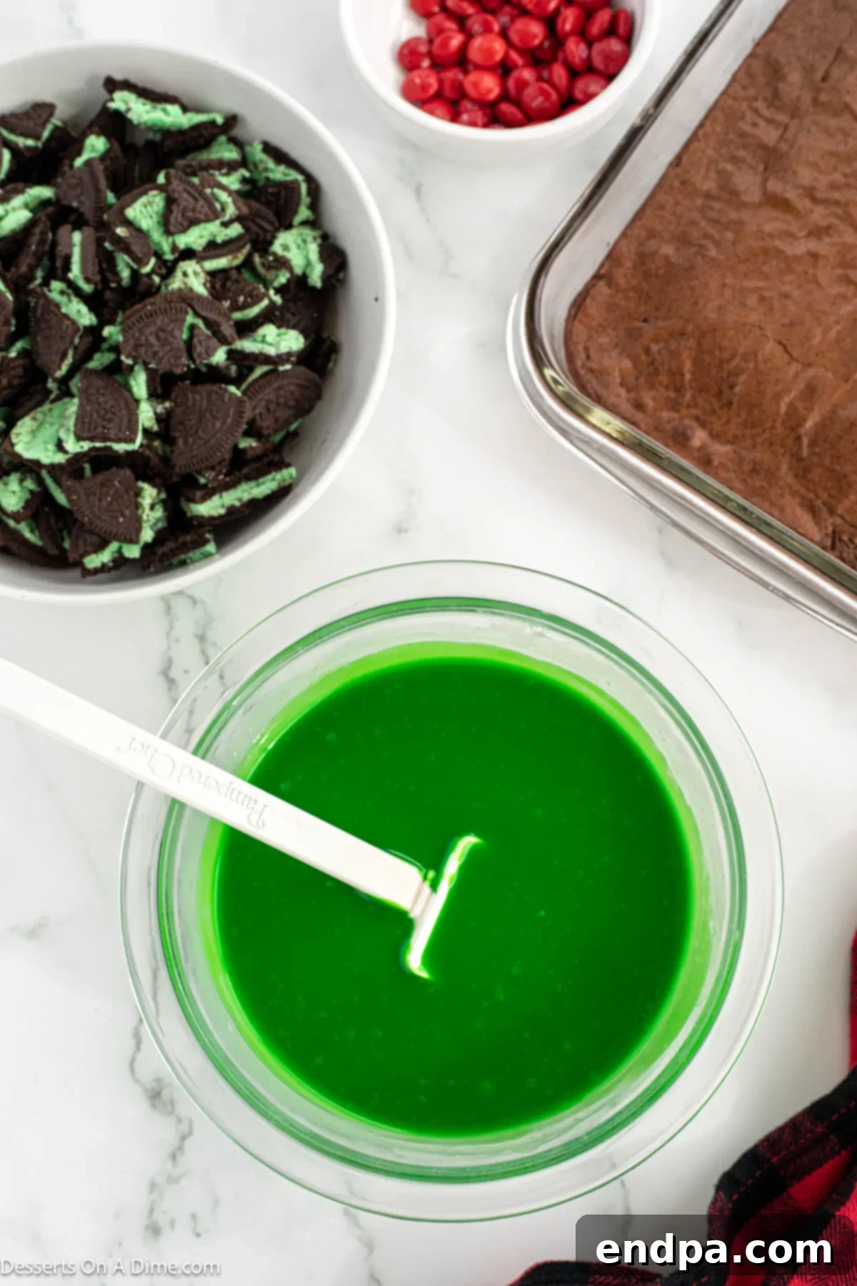 Grinch Green Brownies 8 Green gel food coloring being added to the melted white chocolate mixture in a bowl.