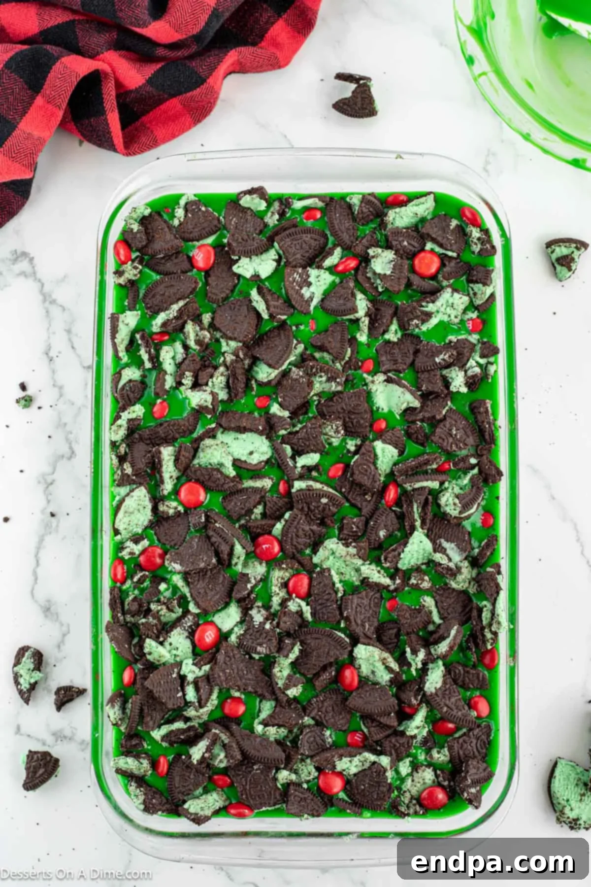 Grinch Green Brownies 10 Crushed Oreo cookies and red M&M candies sprinkled generously over the green-topped brownies.