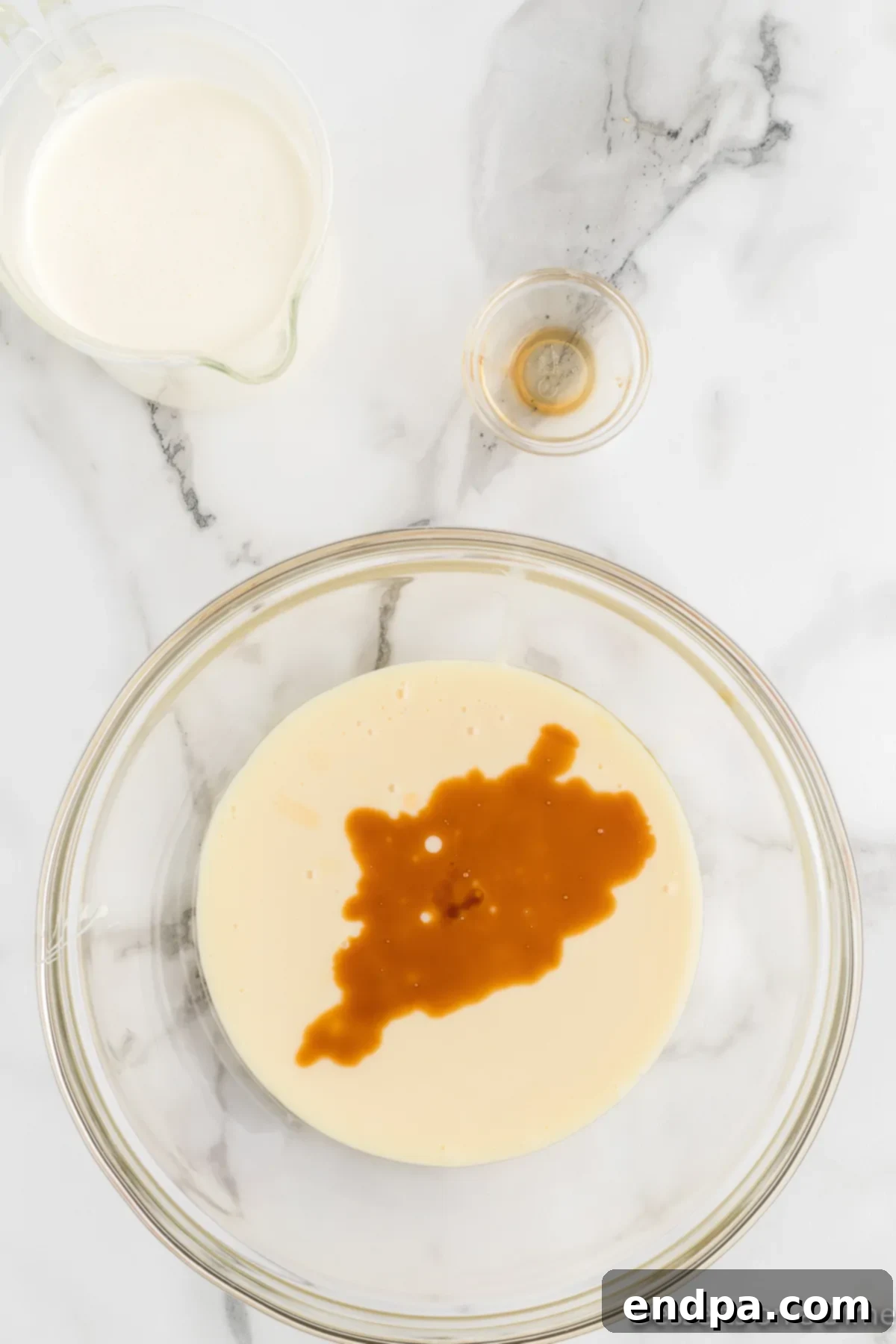 Decadent Homemade Snickers Ice Cream 5 A bowl containing sweetened condensed milk mixed with vanilla extract.