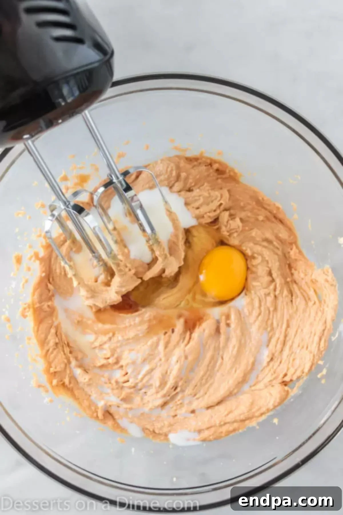 Butter, sugar, and peanut butter being creamed together in a mixing bowl until fluffy.