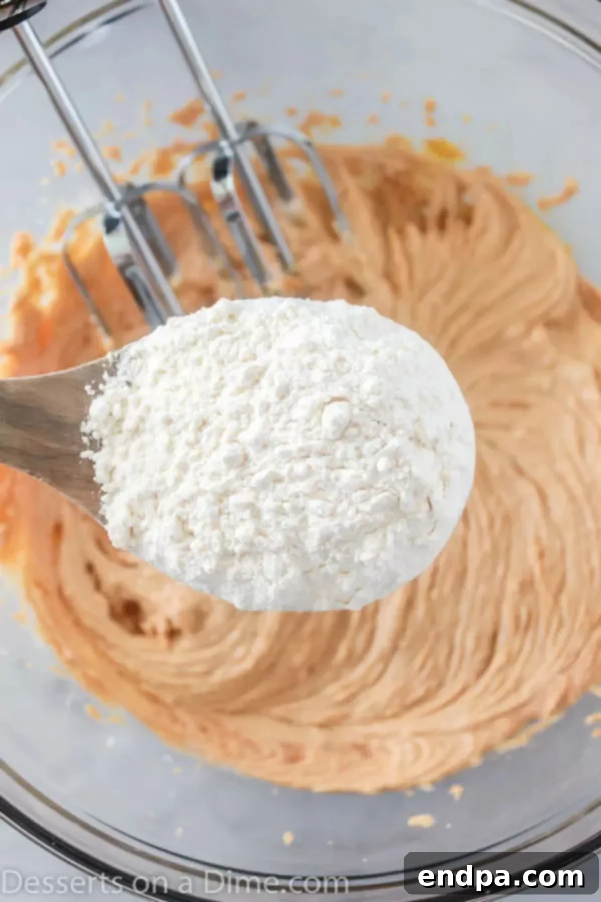 Wet and dry ingredients combined together in a large mixing bowl, forming cookie dough.