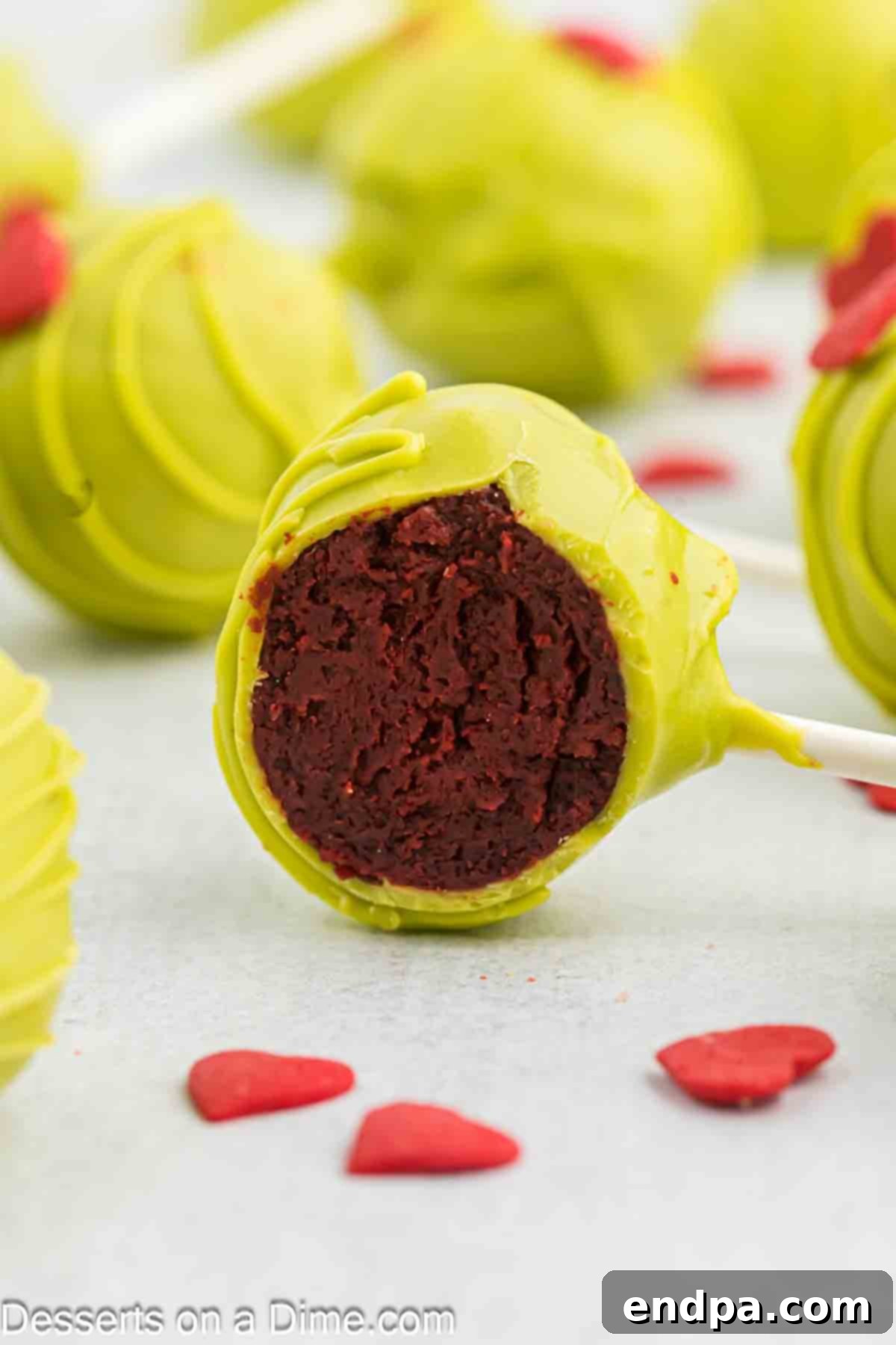 Grinchmas Cake Pops 12 A close-up of a perfectly formed Grinch Cake Pop, showing the smooth green coating and delicate red heart.
