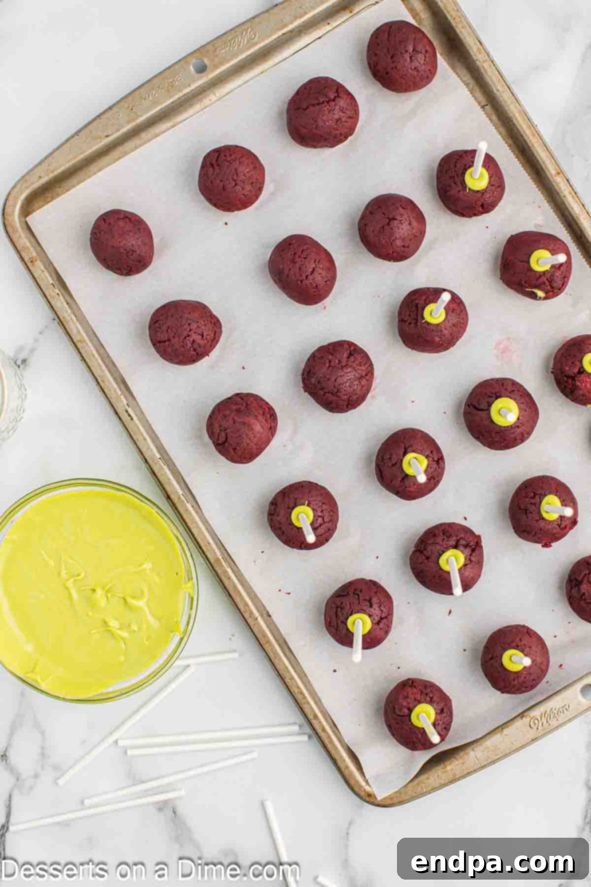 Grinchmas Cake Pops 8 Lollipop sticks being dipped into green candy melt and then inserted into cake balls.