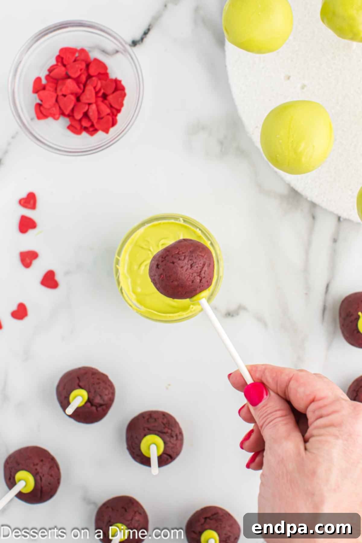 Grinchmas Cake Pops 9 Grinch Cake Pops being dipped into the smooth, melted green candy coating.