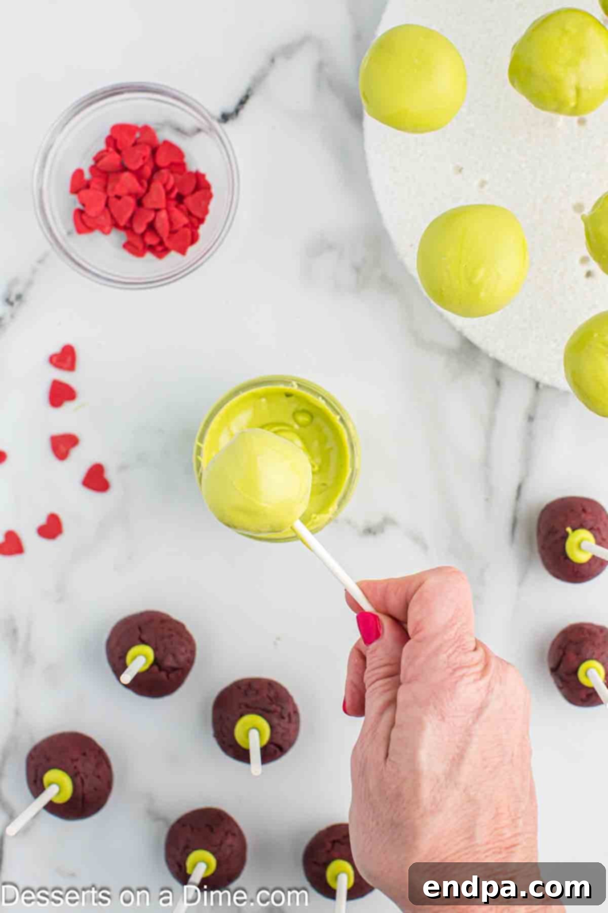 Grinchmas Cake Pops 10 Excess green candy coating dripping off a freshly dipped Grinch Cake Pop.