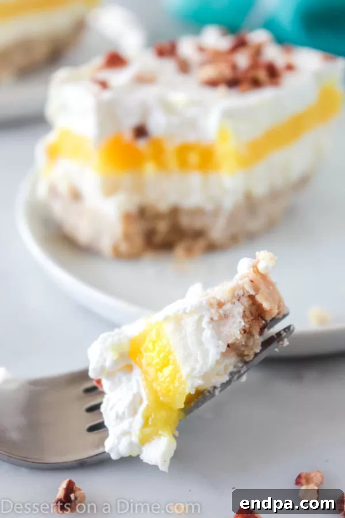Close up image of a slice of Lemon Lush Dessert with a bite taken out, showing the creamy layers.