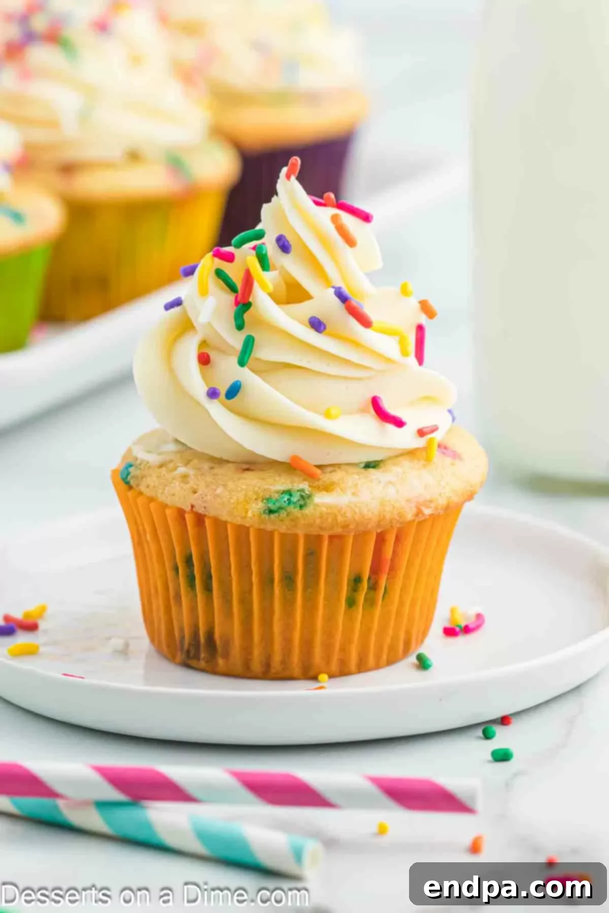 A close-up of a perfectly frosted confetti cupcake, adorned with more rainbow sprinkles.