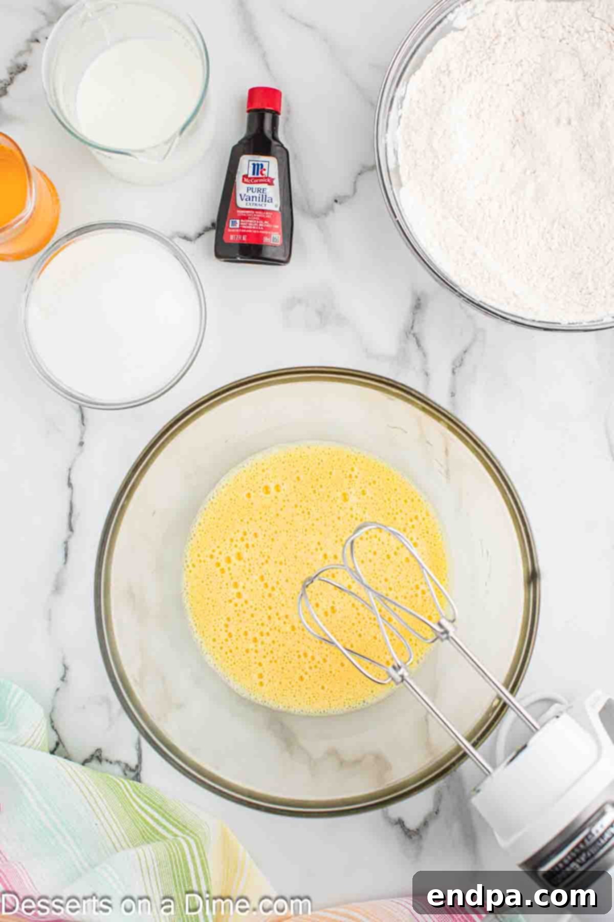 Eggs and sugar being beaten together in a large mixing bowl.