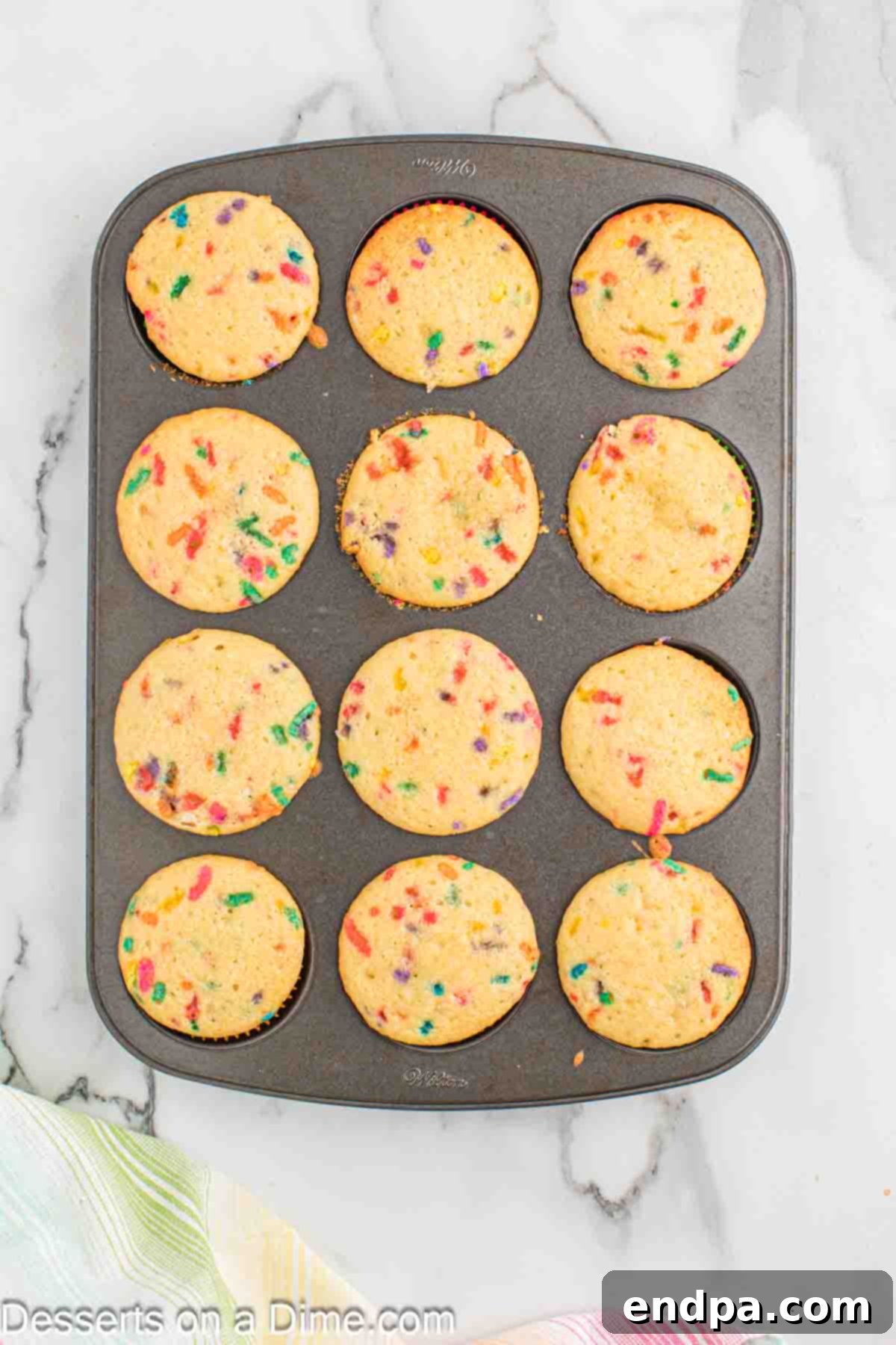 Baked confetti sprinkle cupcakes cooling on a wire rack.