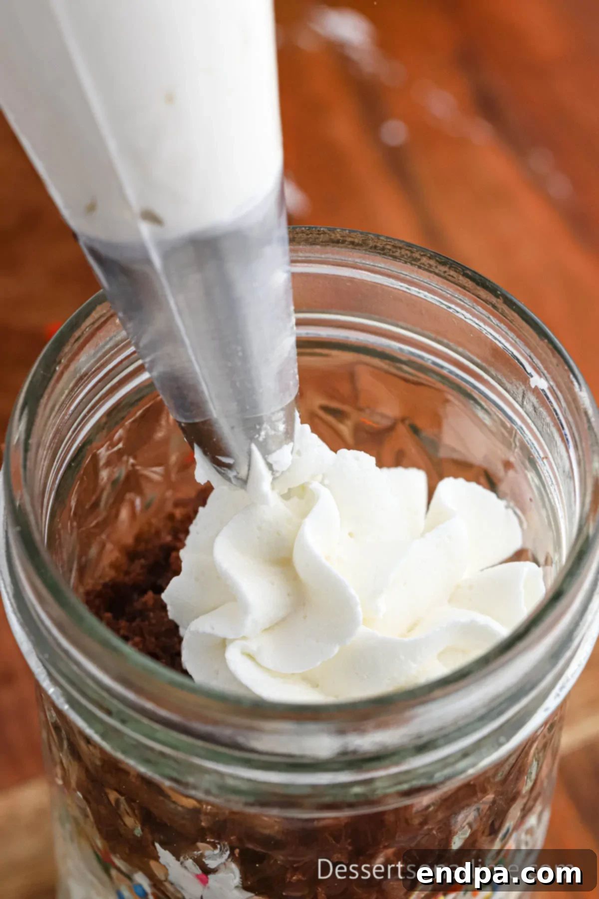 Portable Cupcake Perfection 11 The final layer of frosting and sprinkles crowning a cupcake in a jar.